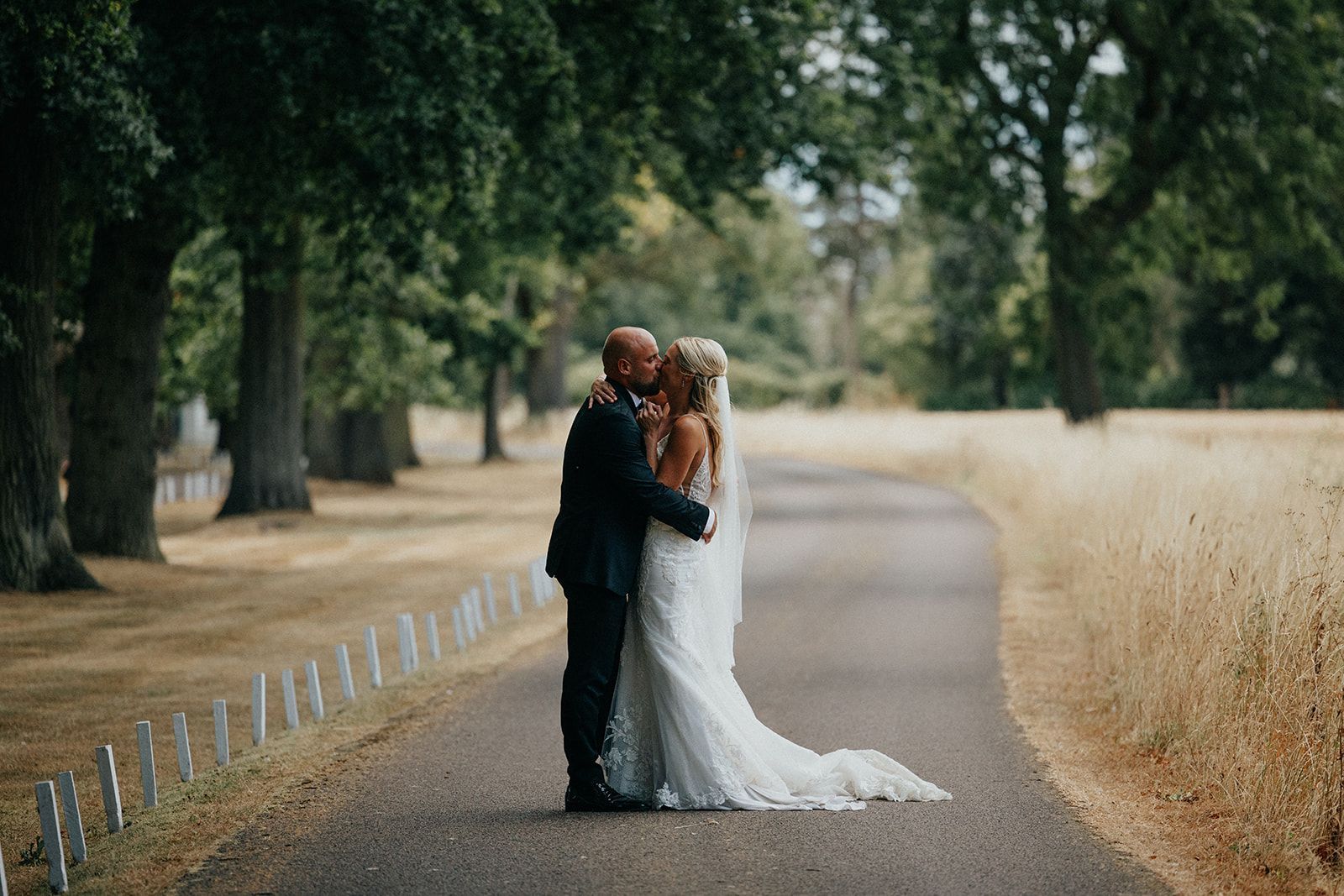 A bride and groom are kissing on the side of a road.