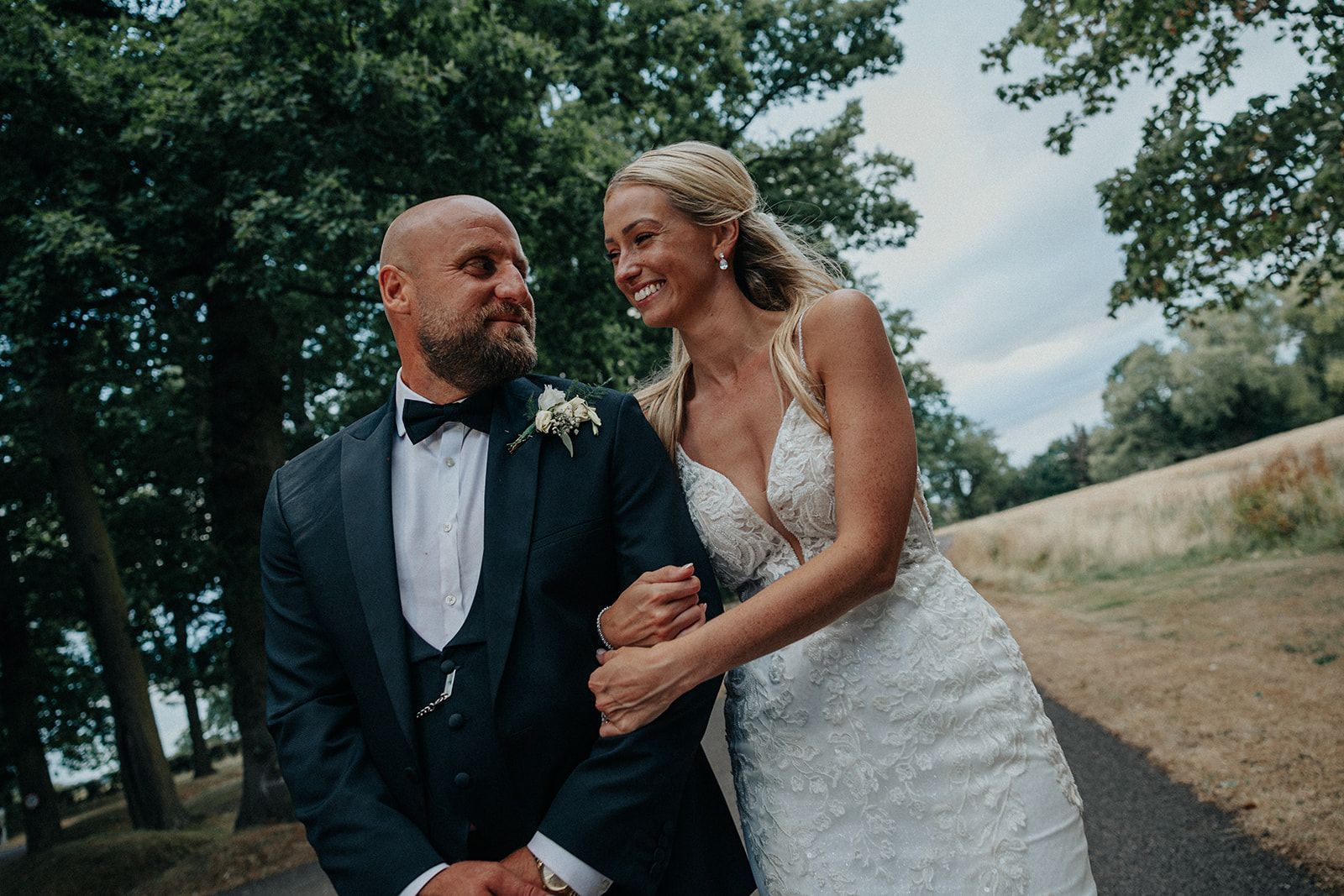 A bride and groom are standing next to each other on a path.