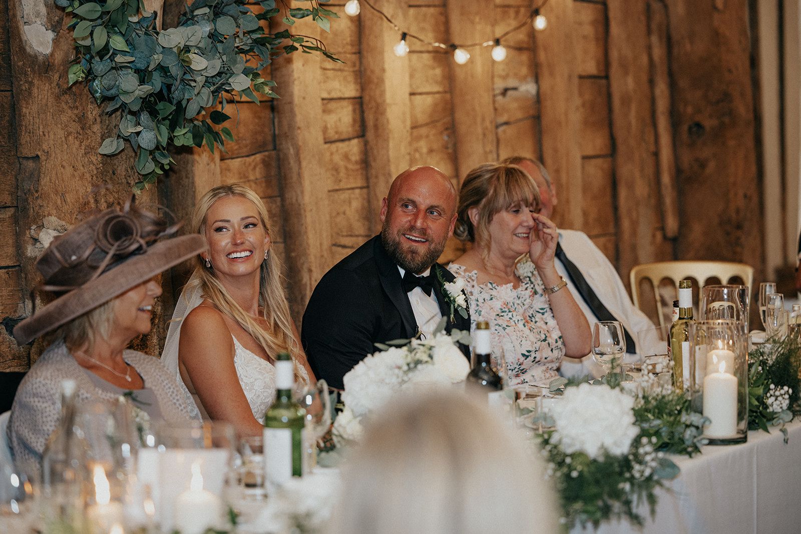 A group of people are sitting at a long table at a wedding reception.