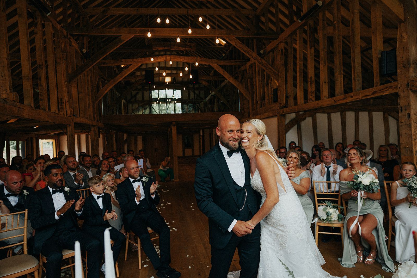 A bride and groom are kissing in front of their wedding guests.
