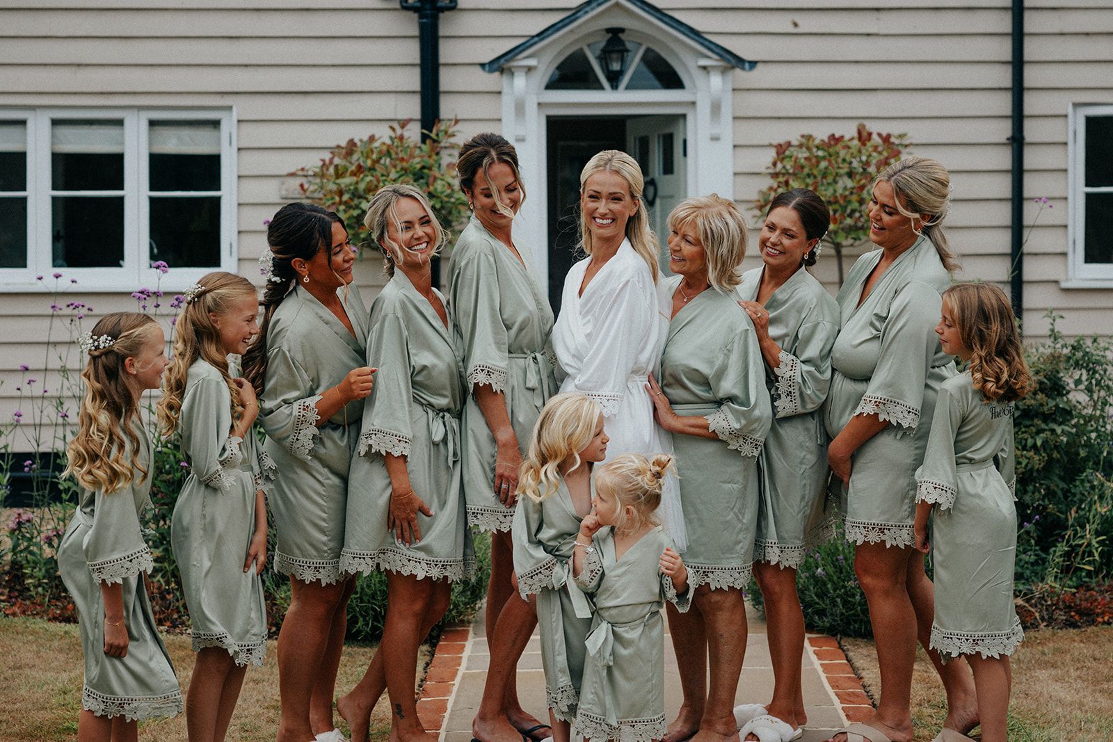 A bride and her bridesmaids are posing for a picture in front of a house.