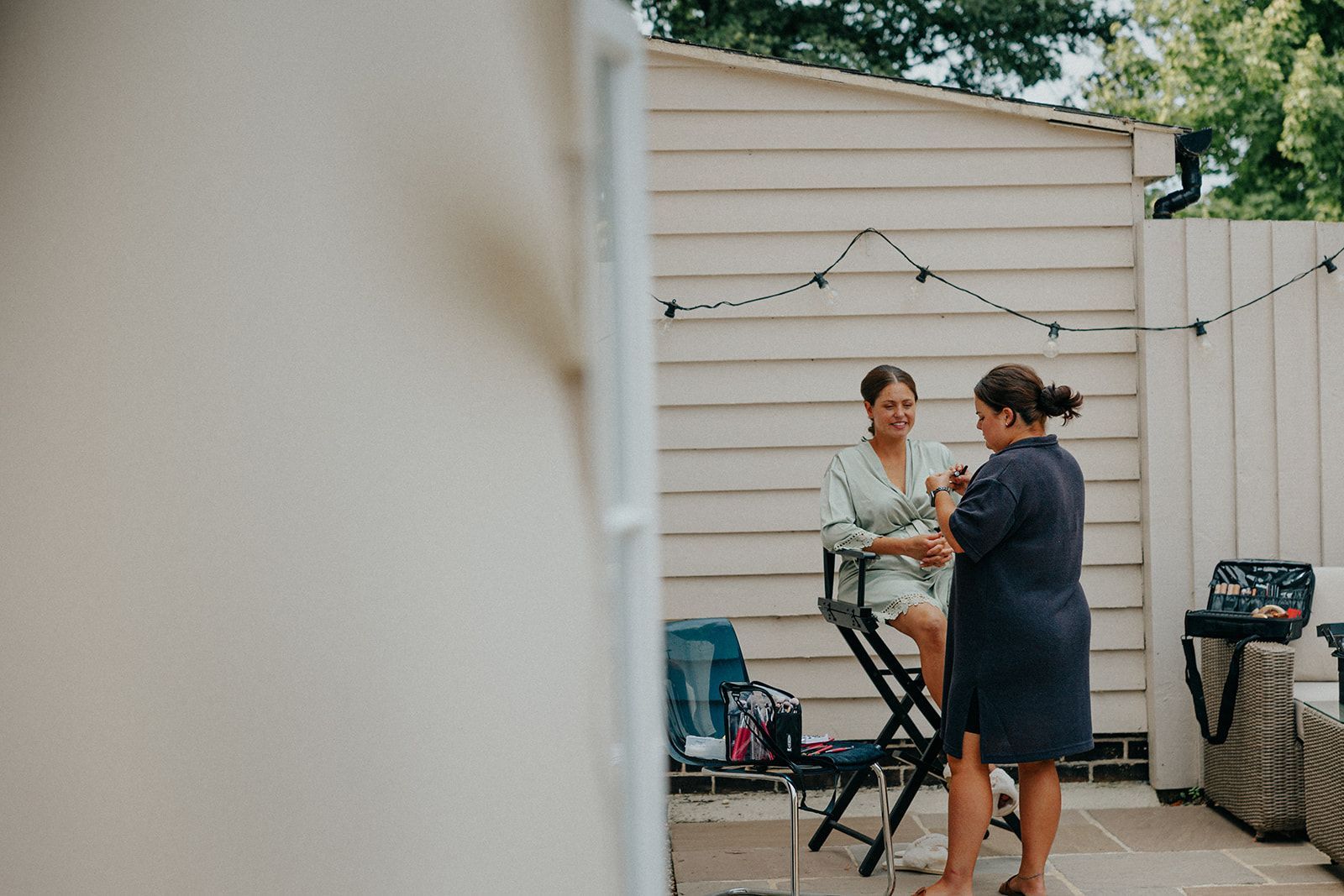 A woman is sitting in a chair getting her hair done by a makeup artist.