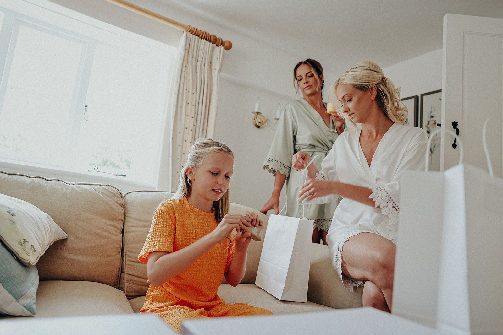 A little girl is sitting on a couch with two women.