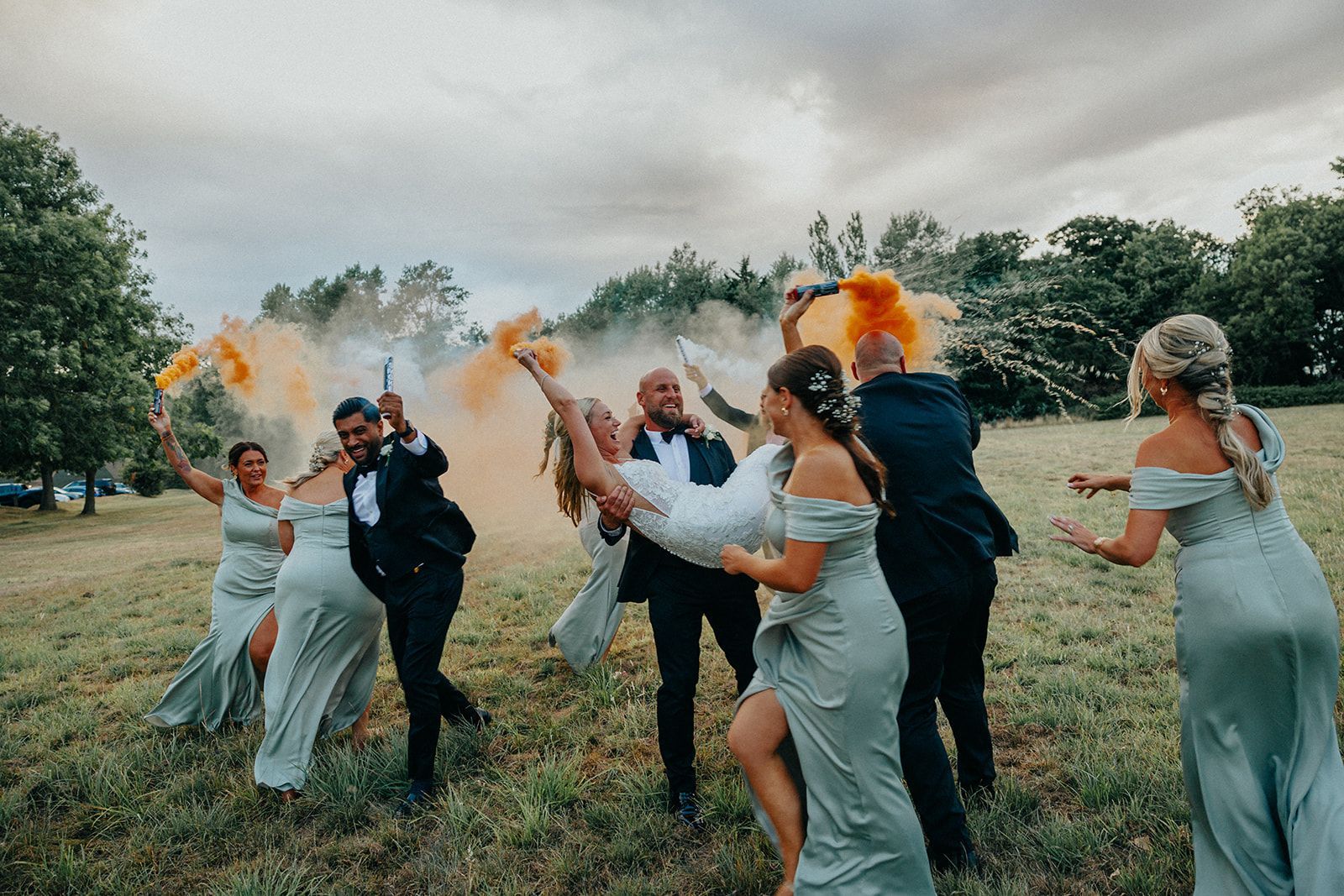 A bride and groom are being carried by their bridesmaids in a field.