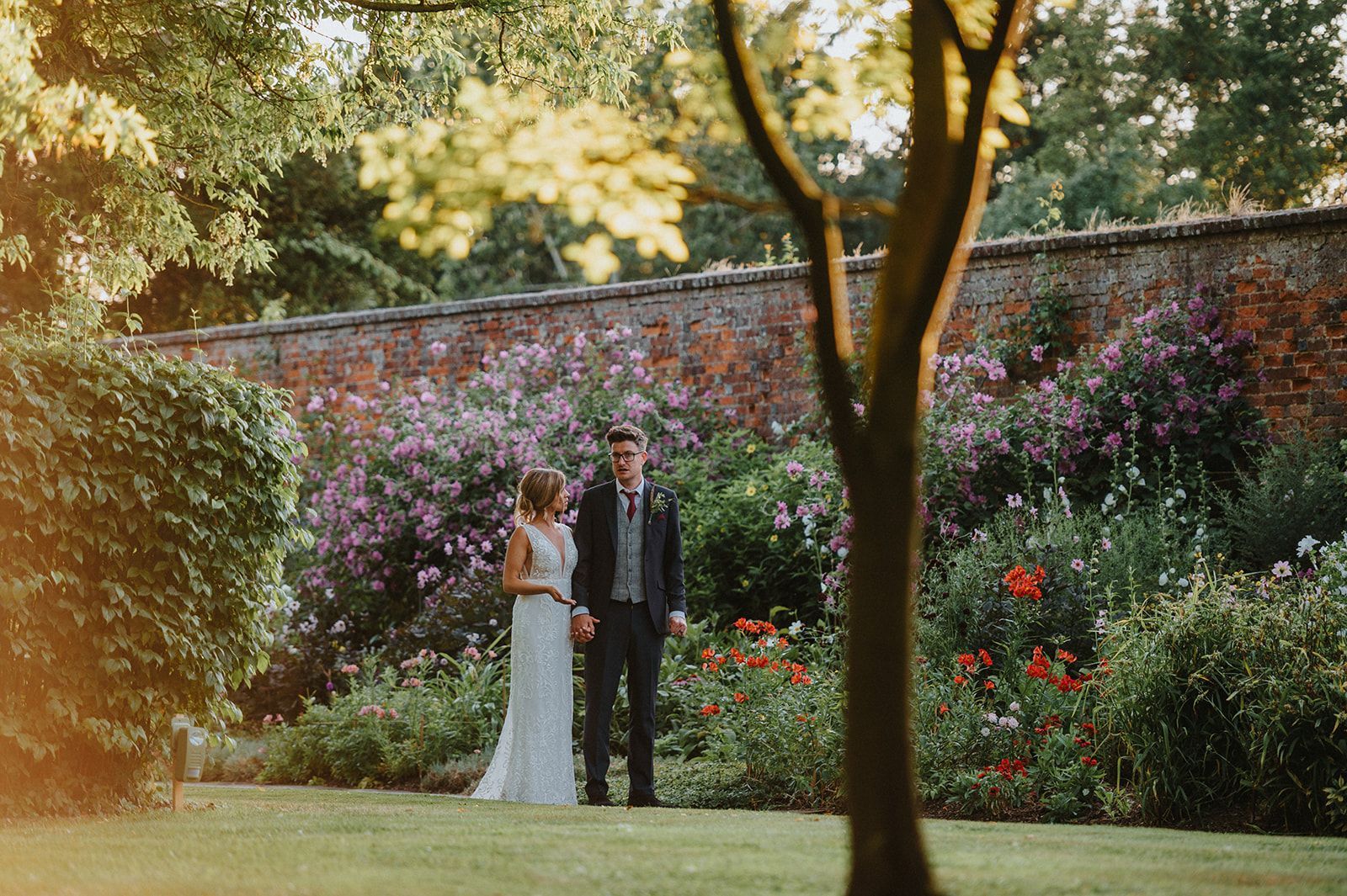 A bride and groom are standing next to each other on a path.