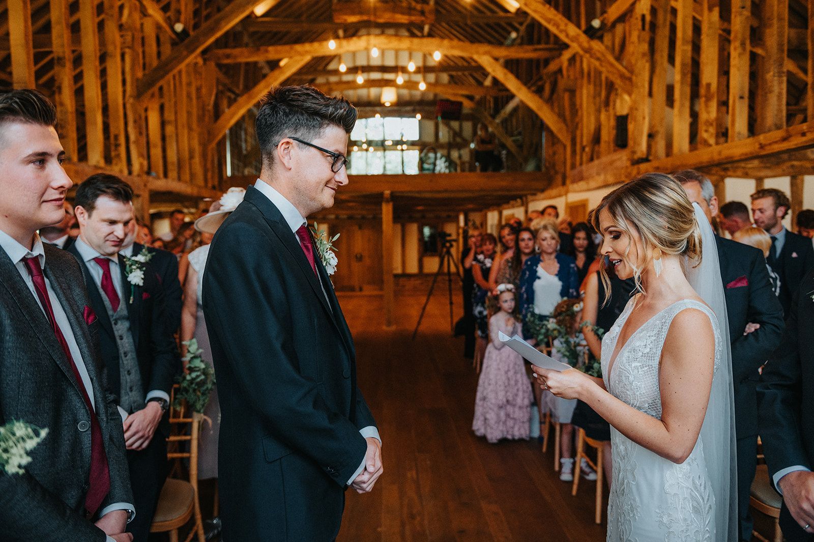 A bride and groom are holding hands during their wedding ceremony in a barn.