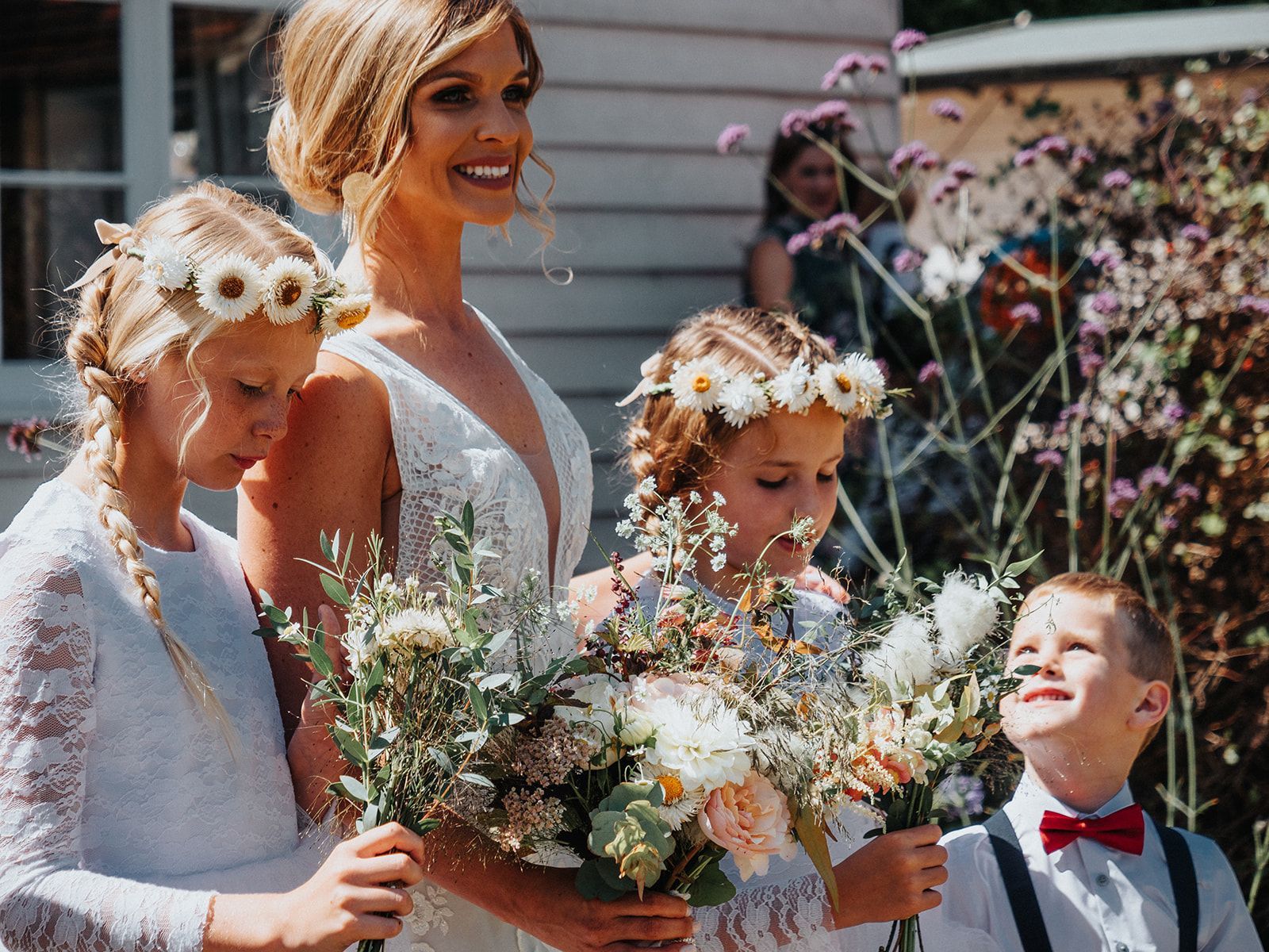 A bride and her flower girls are holding bouquets of flowers.