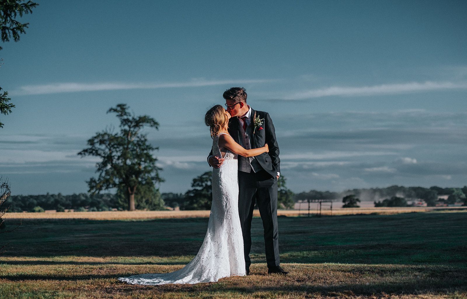 A bride and groom are kissing in a field.