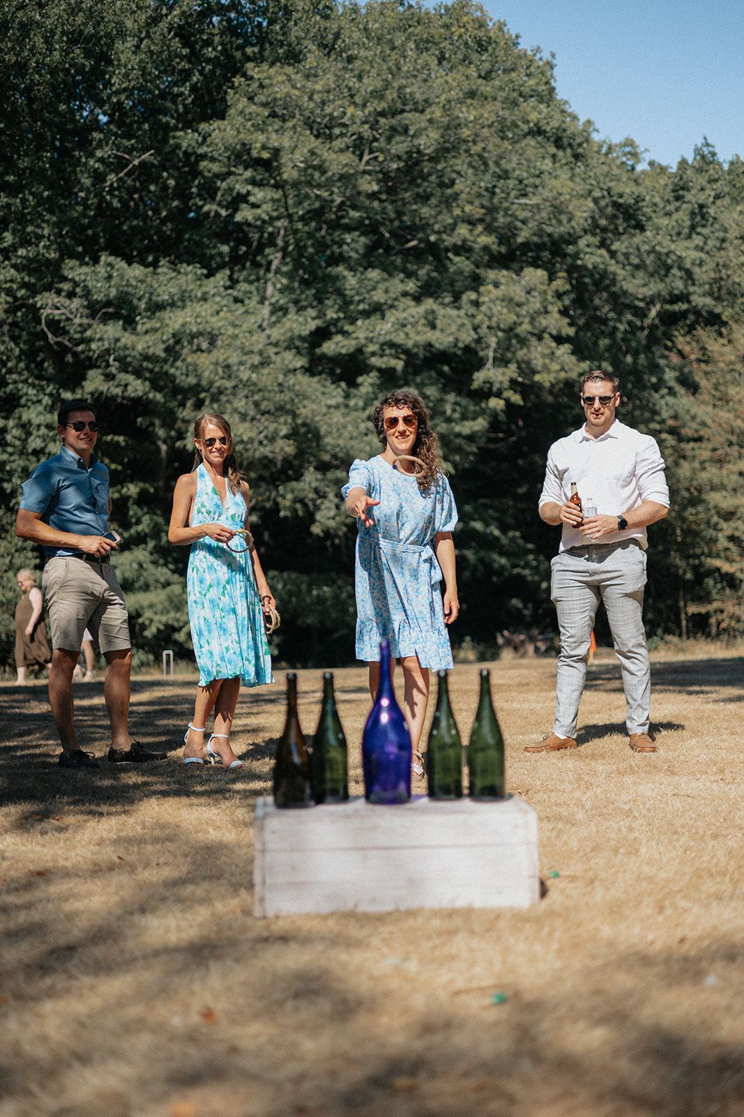A group of people are standing in a field with bottles of wine.