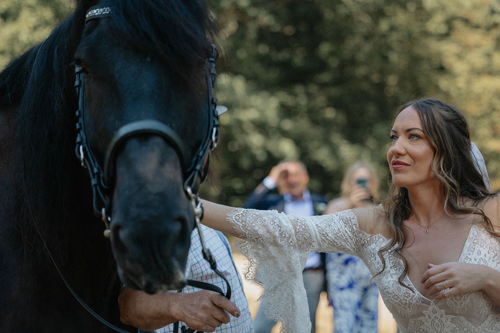 A bride and groom are standing next to a black horse.
