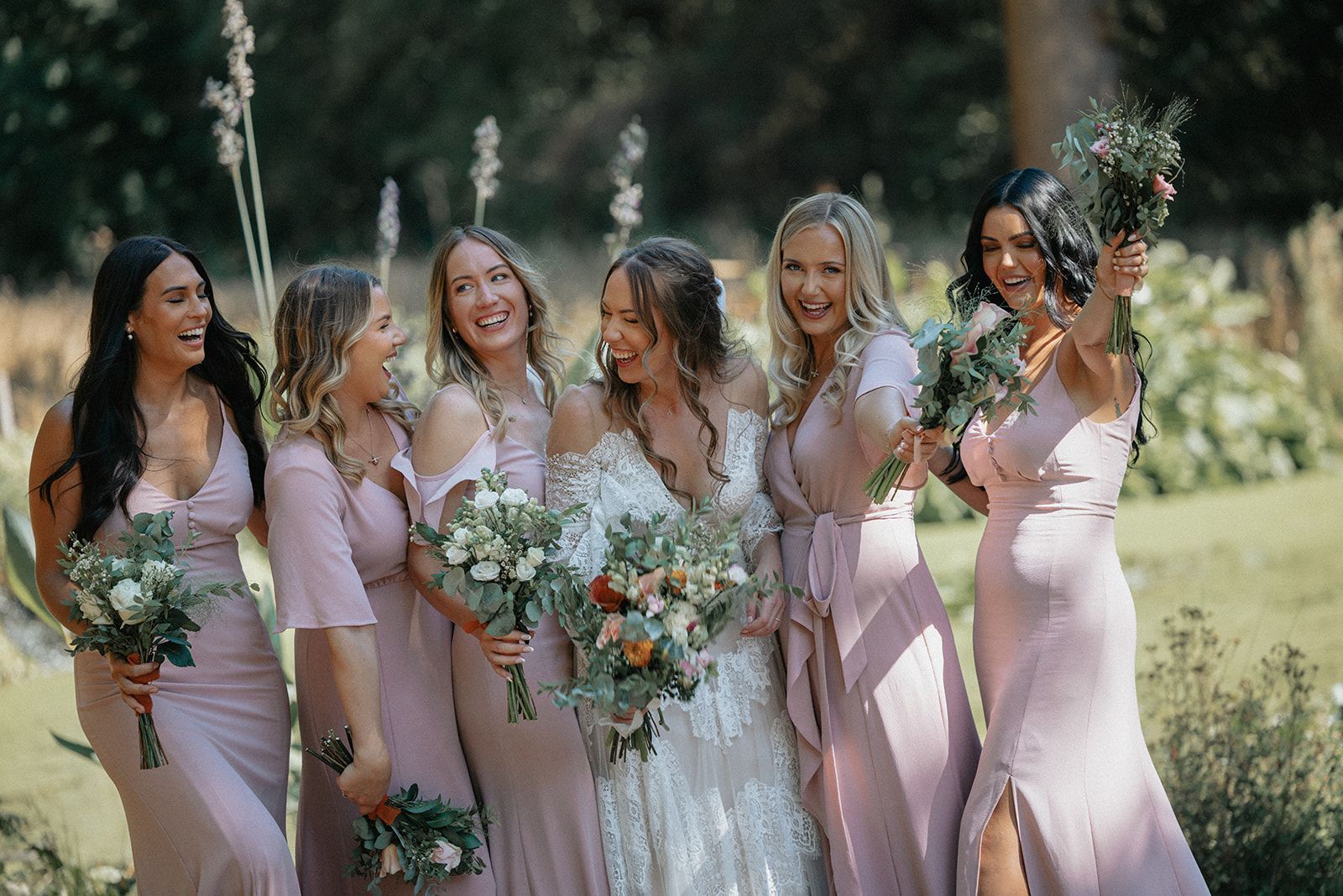 A bride and her bridesmaids are posing for a picture in a field.
