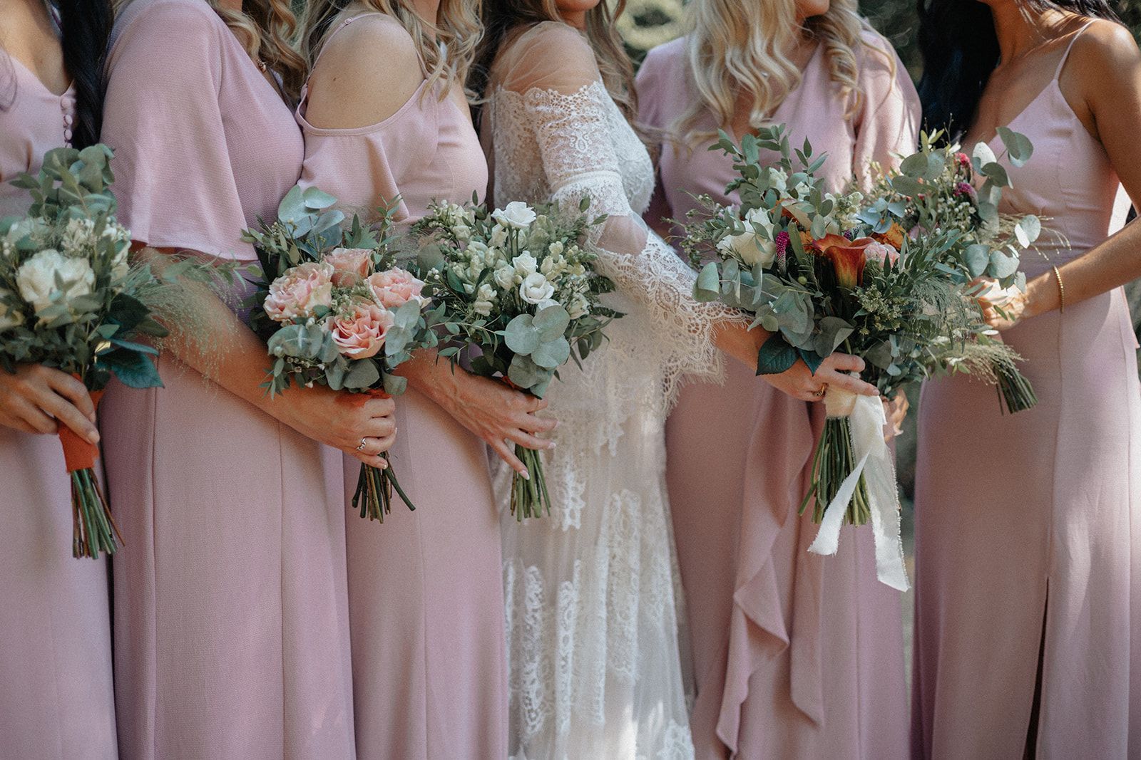 A bride and her bridesmaids are posing for a picture while holding bouquets of flowers.