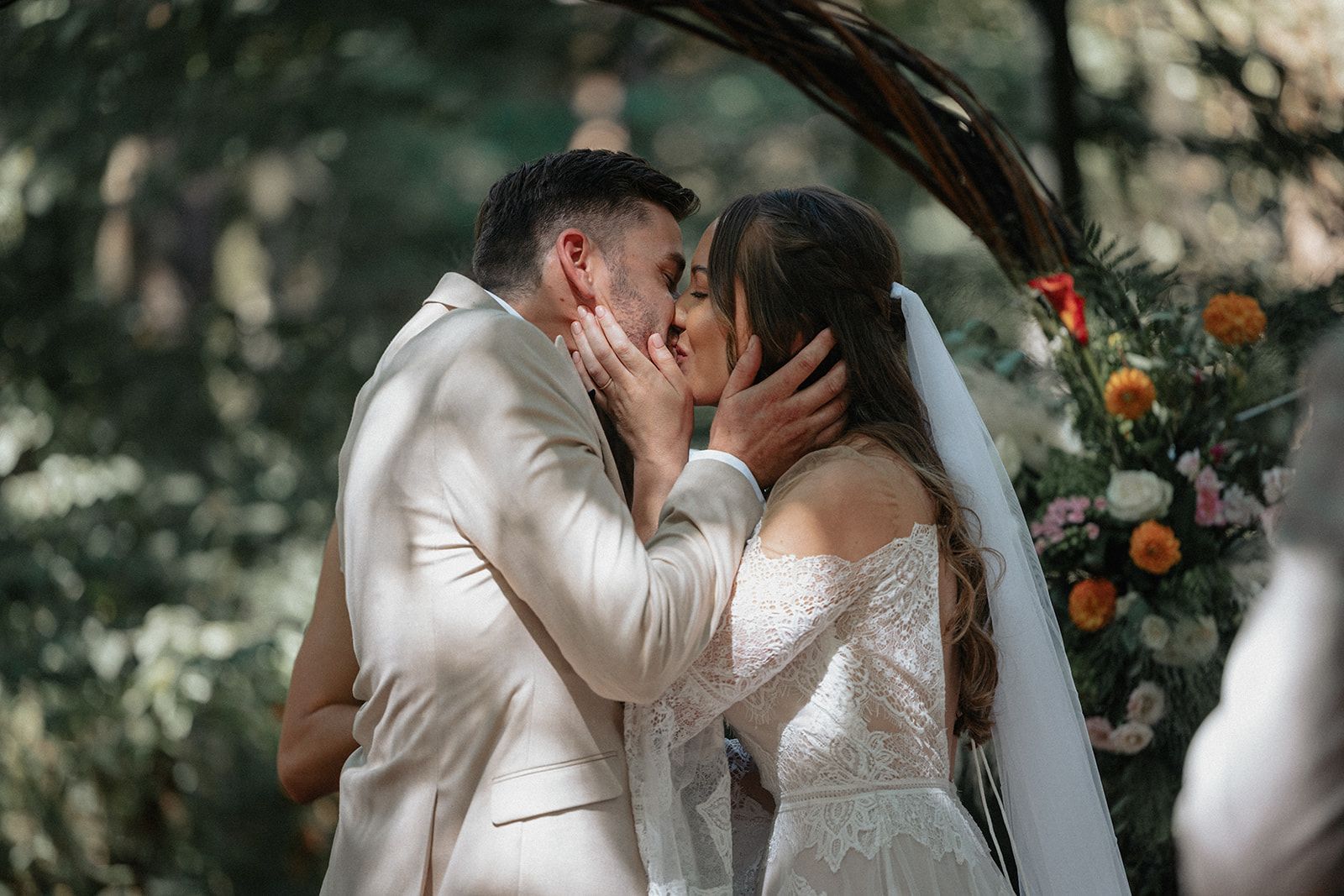 A bride and groom are kissing during their wedding ceremony.
