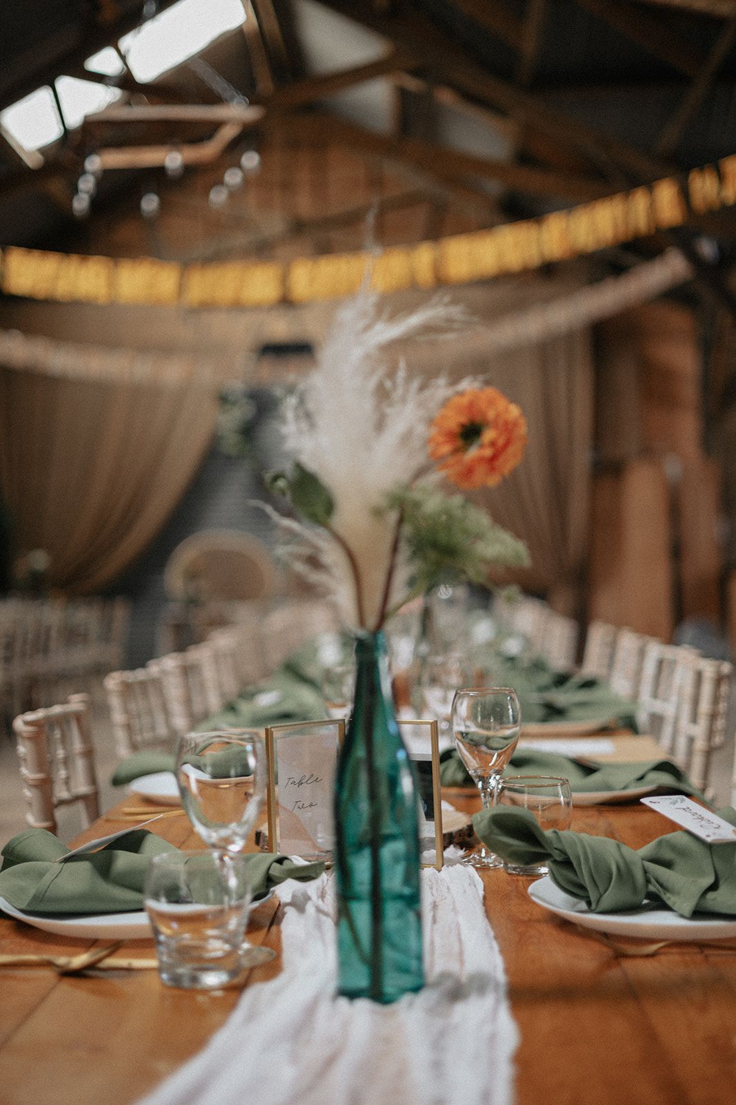 A table set for a wedding reception with a vase of flowers on it.