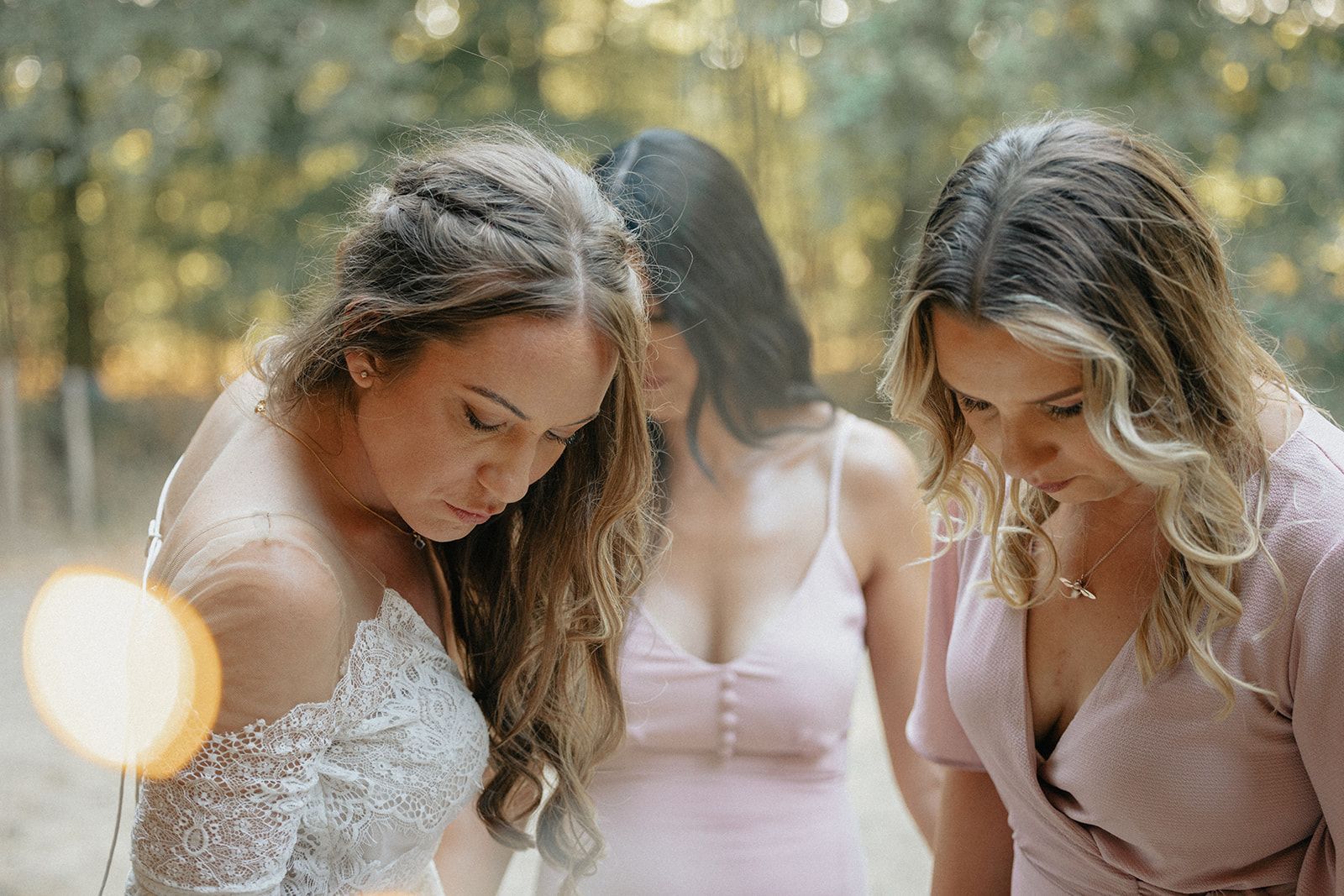 Three women are standing next to each other in a forest.