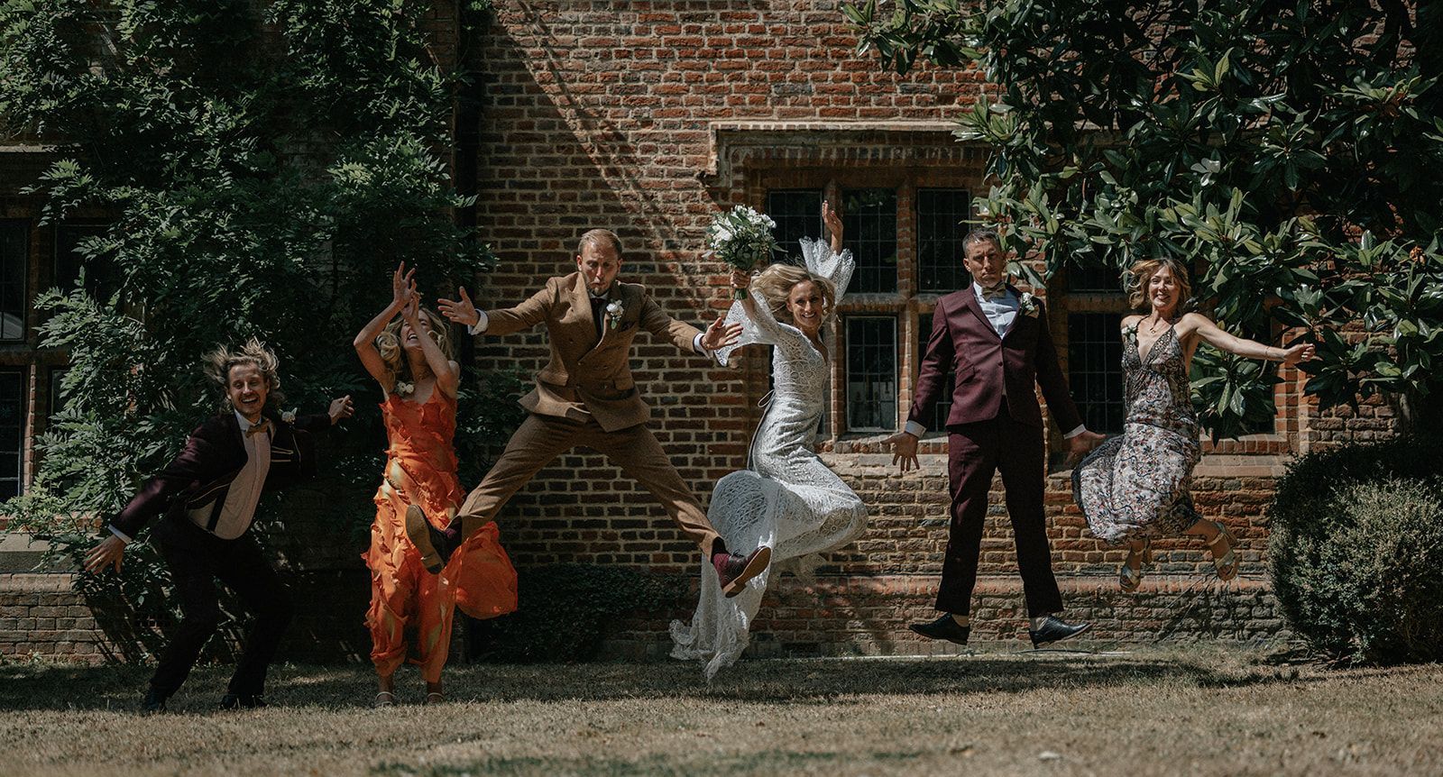 A group of people are jumping in the air in front of a brick building.