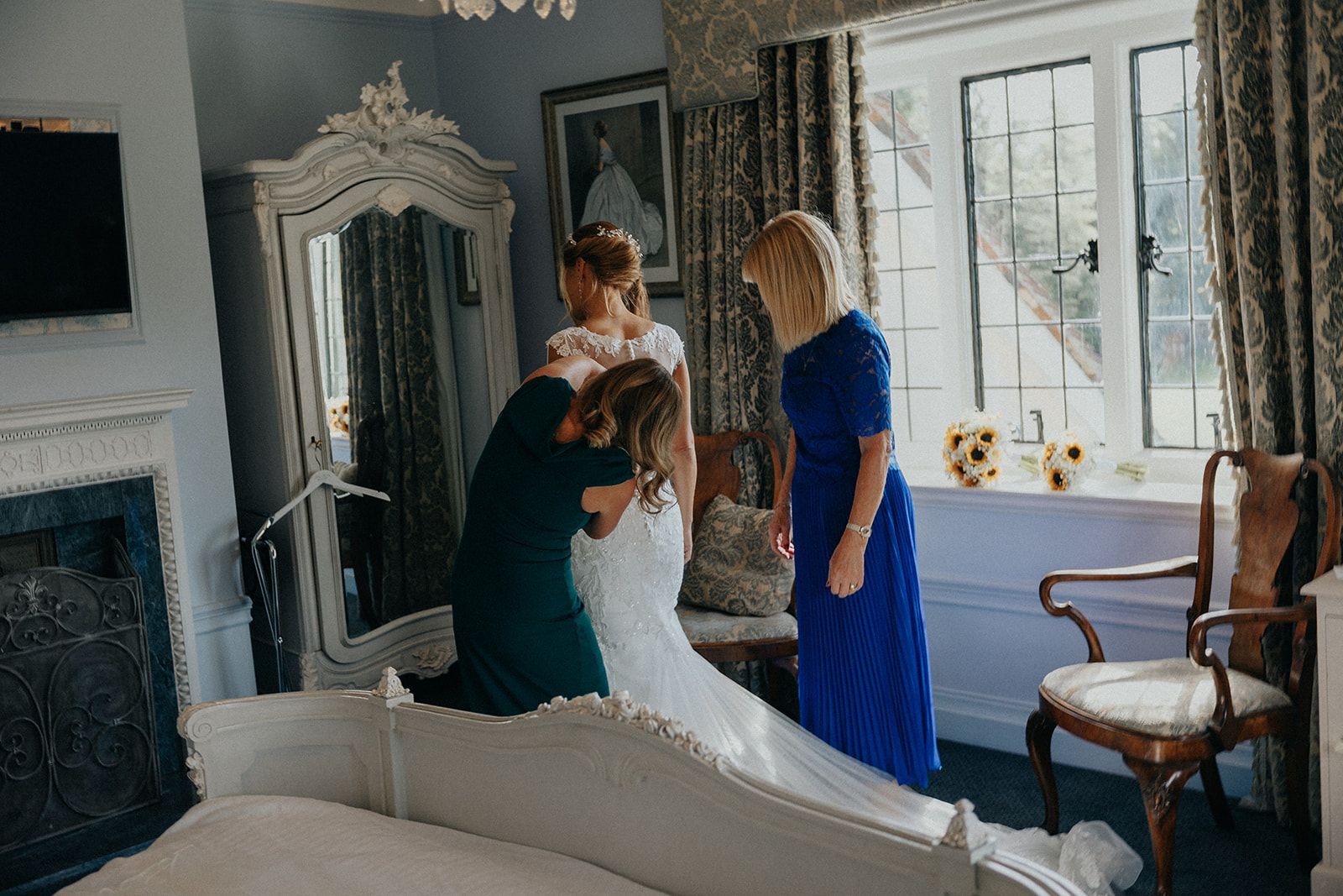 A bride is getting ready for her wedding in a room with her bridesmaids.