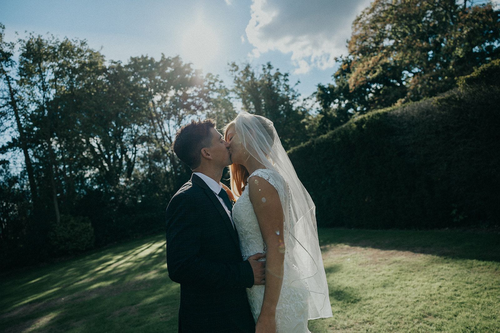 A bride and groom are kissing in a field.