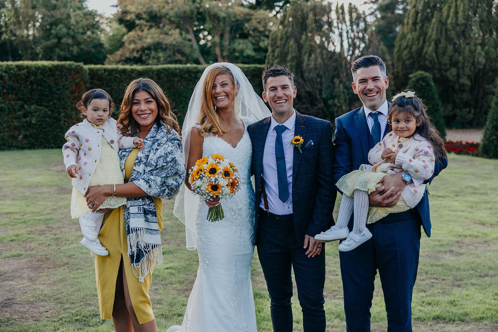 A bride and groom are posing for a picture with their family.