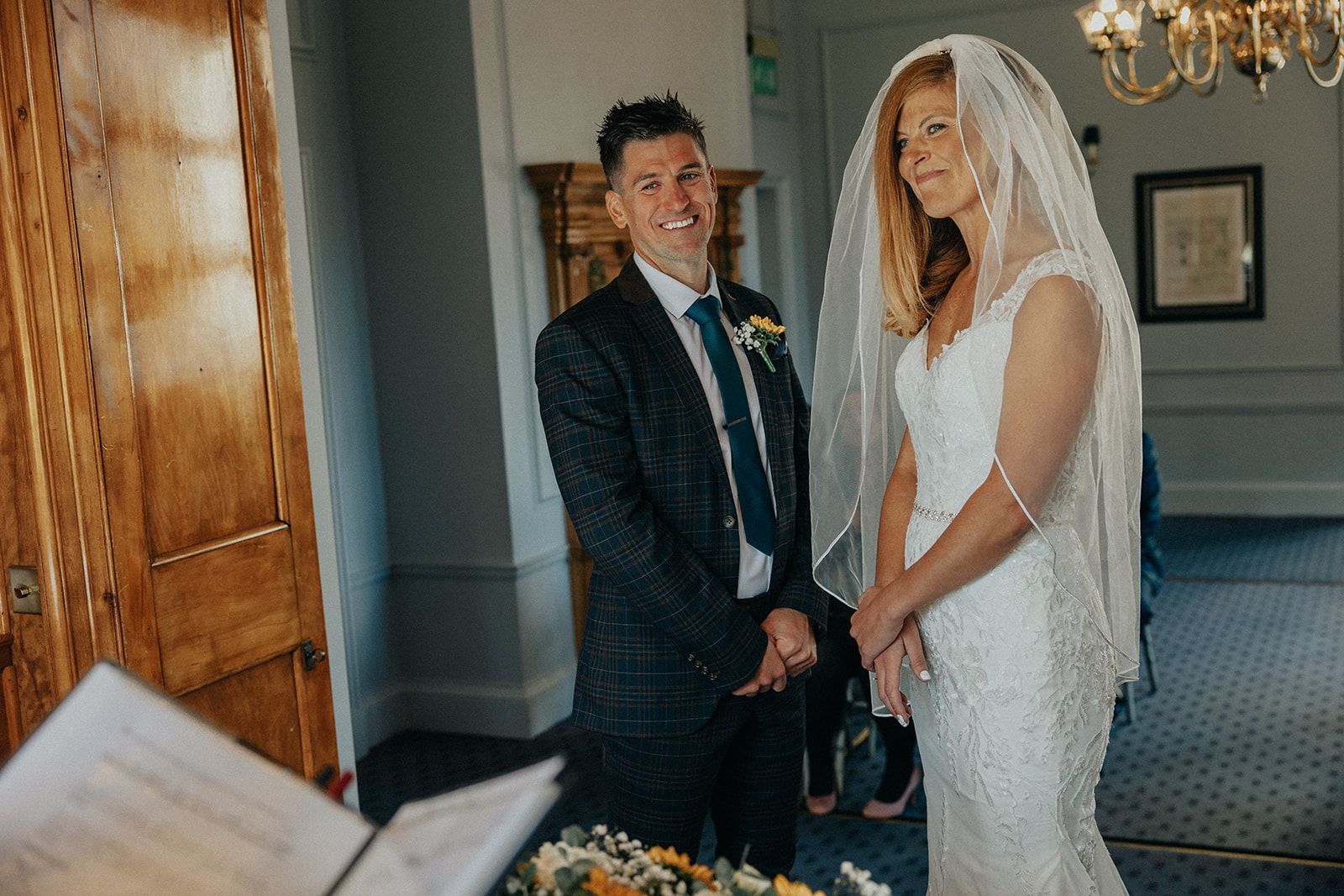 A bride and groom are standing next to each other in a room.