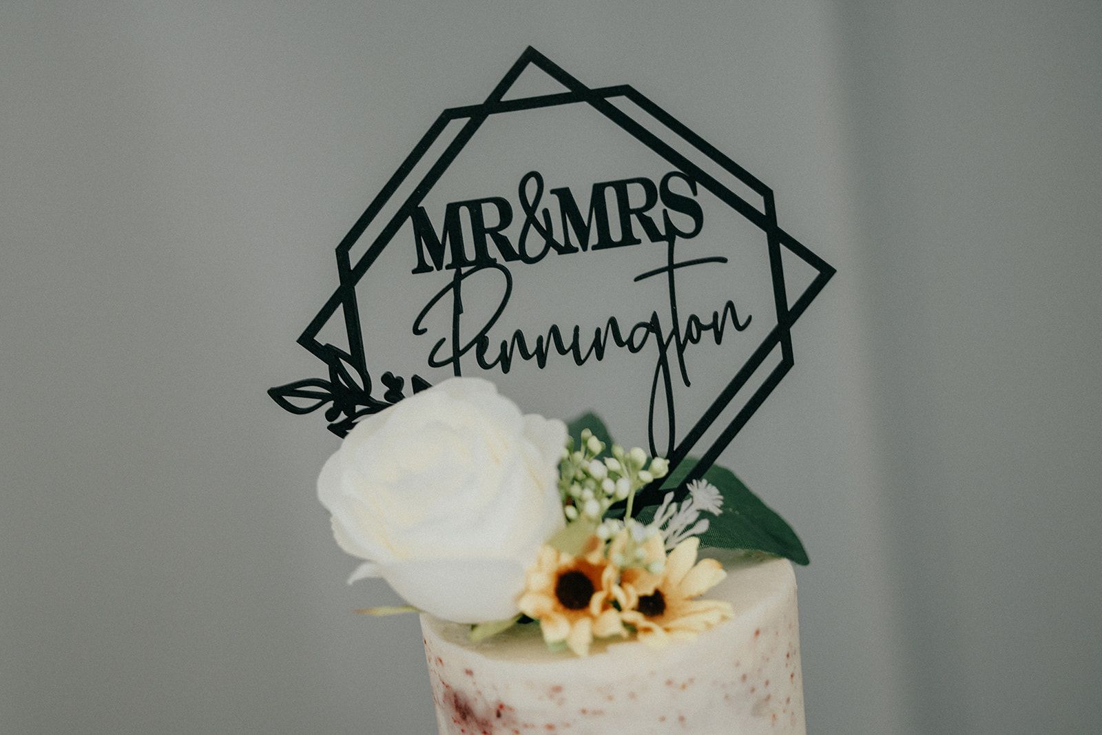 A wedding cake with flowers and a cake topper that says mr and mrs.