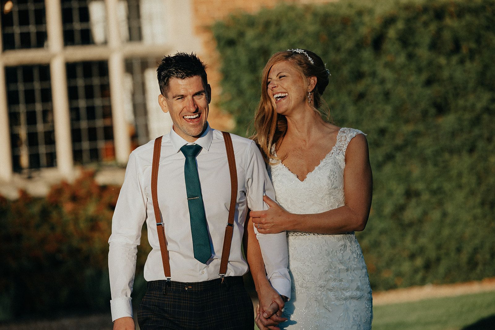 A bride and groom are holding hands and smiling in front of a building.
