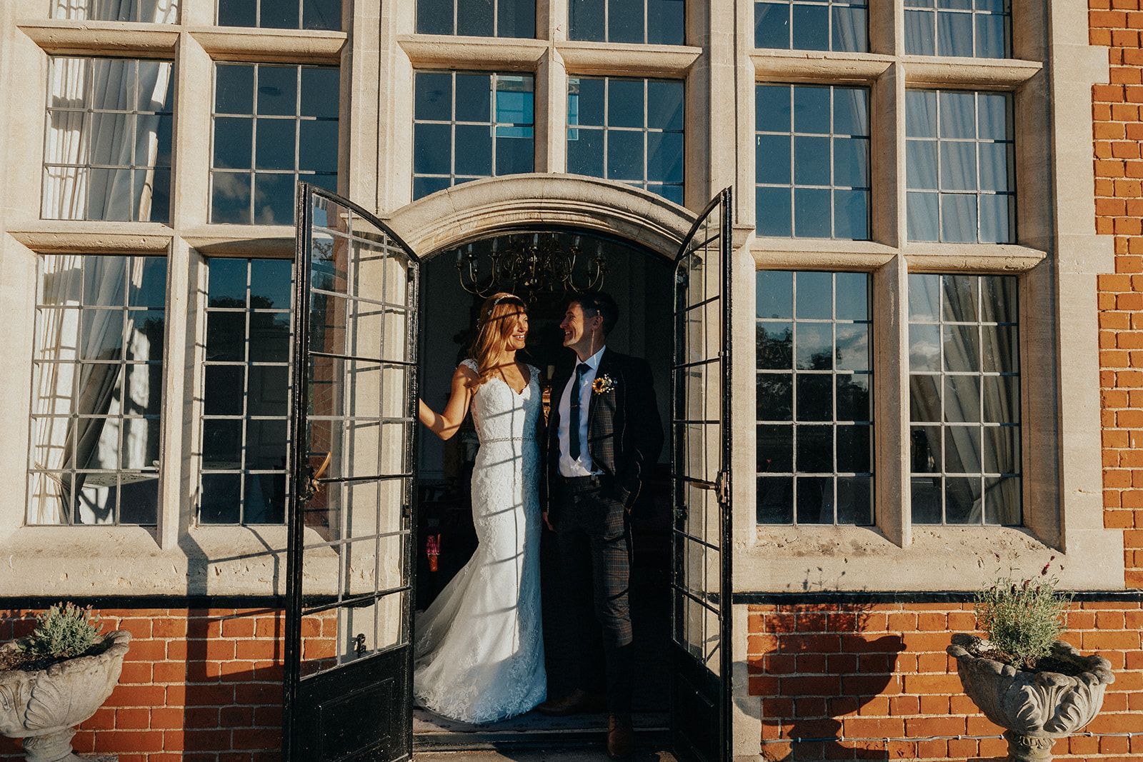 A bride and groom are standing in front of a brick building.