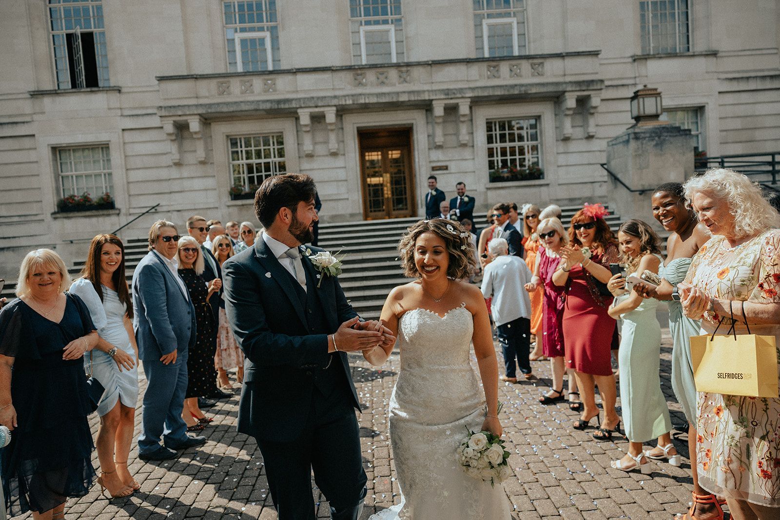 A bride and groom are walking in front of a crowd of people.