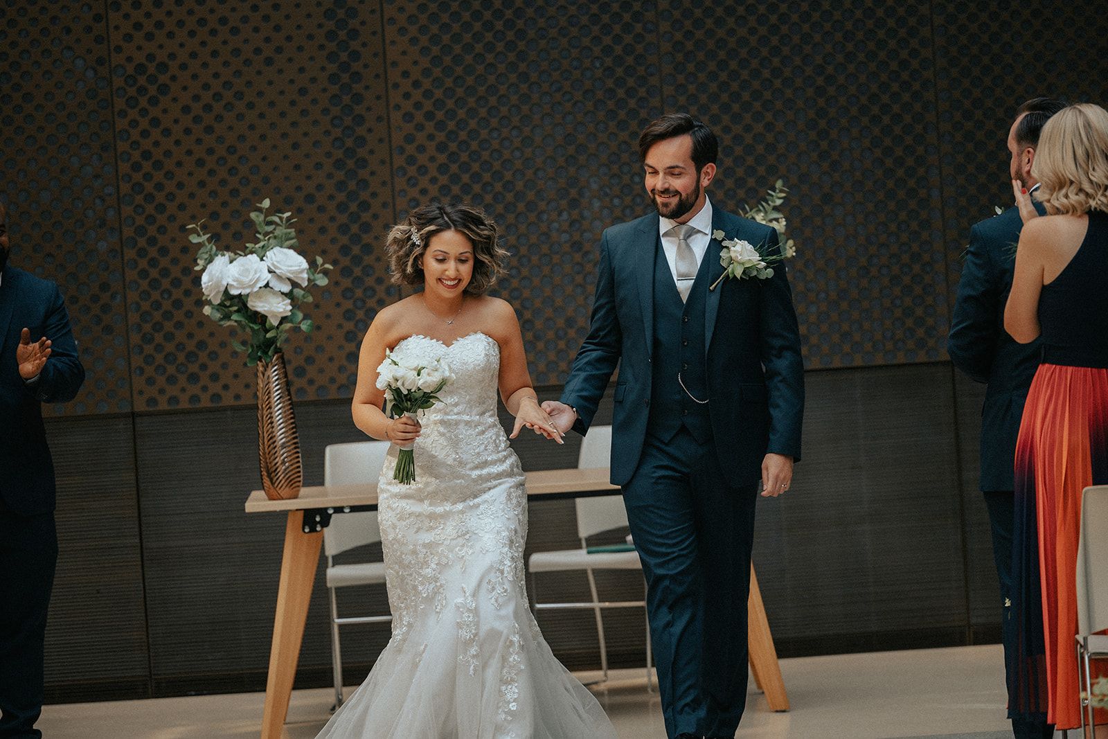 A bride and groom are walking down the aisle at their wedding holding hands.