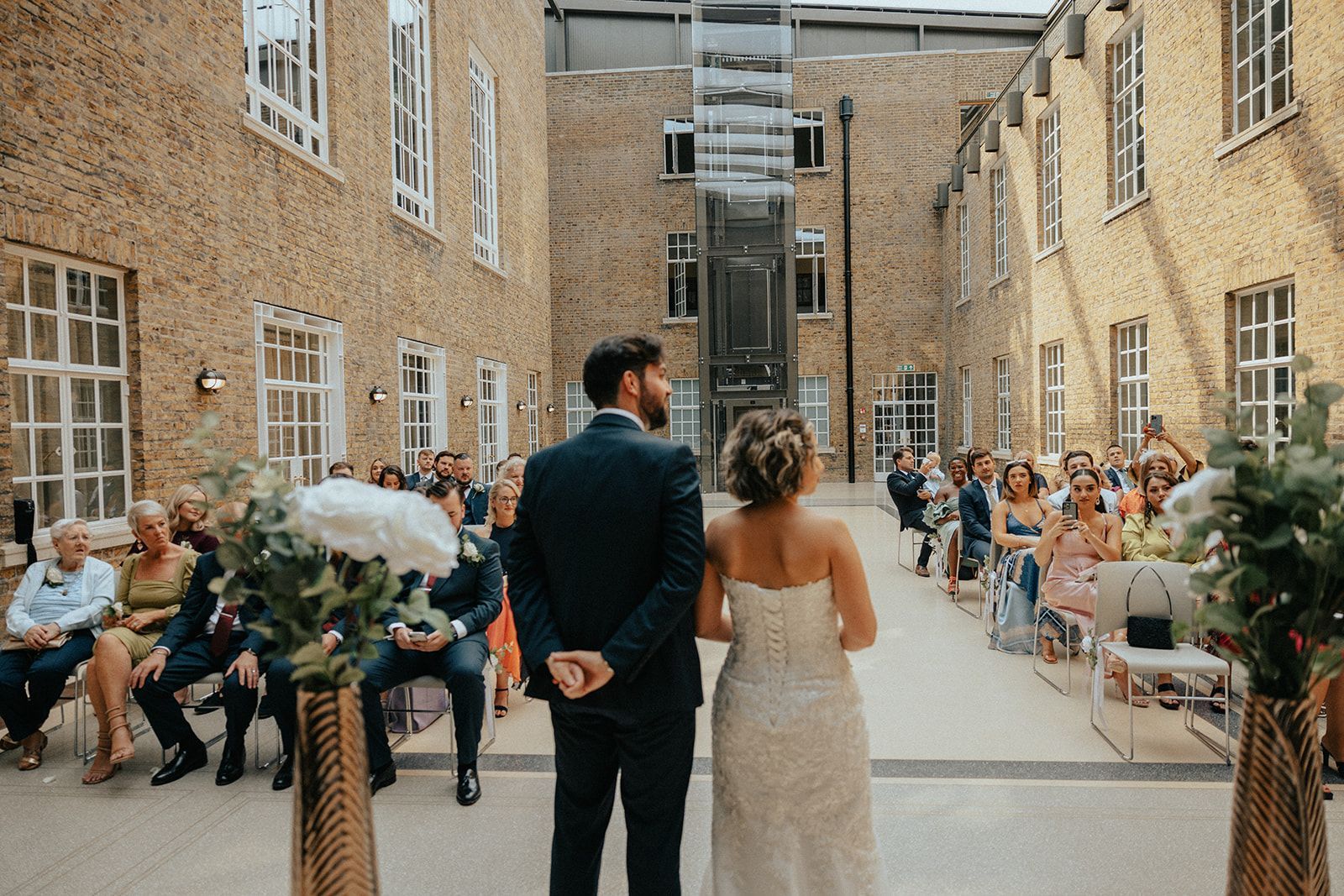 A bride and groom are standing in front of a crowd of people at a wedding ceremony.
