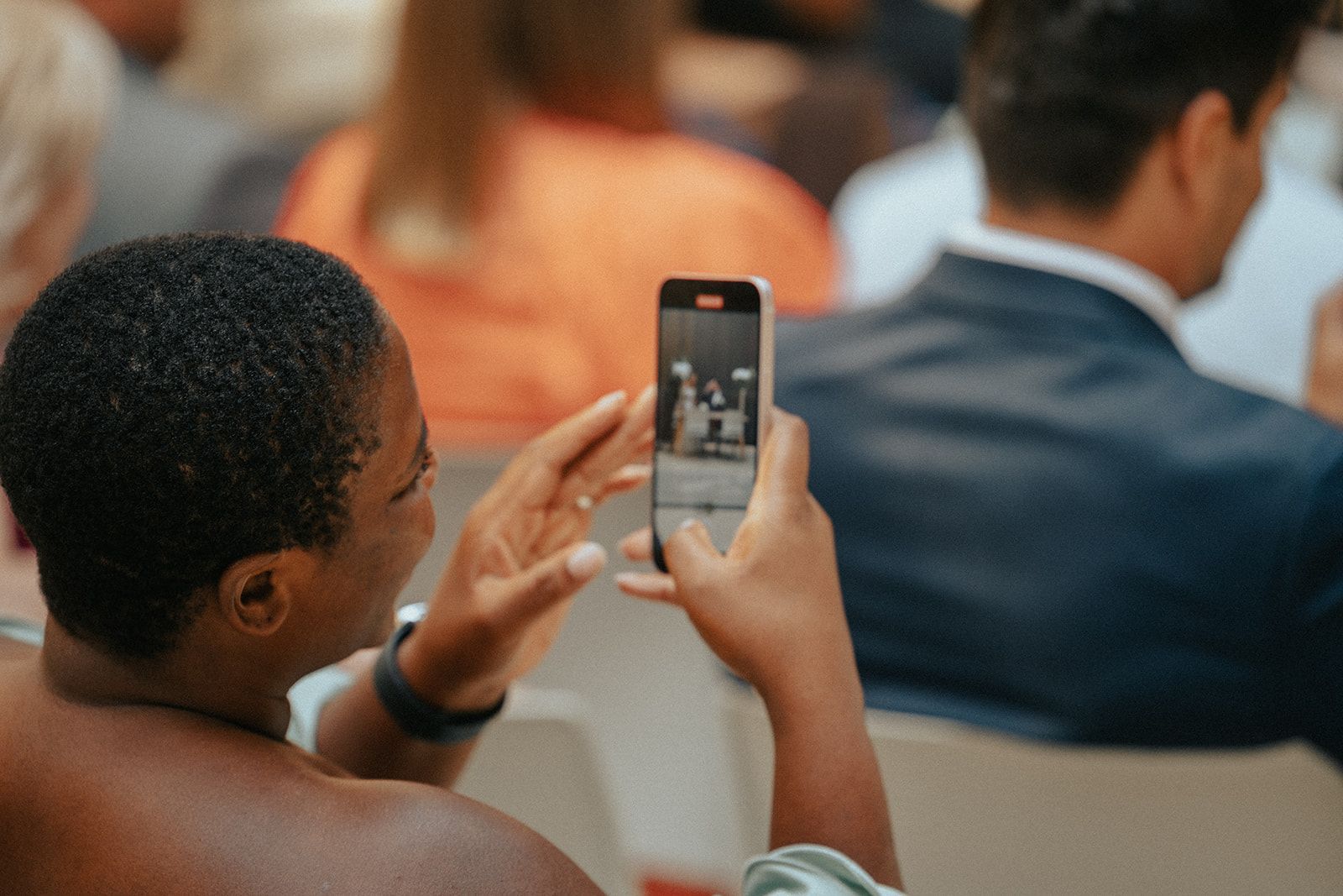 A woman is taking a picture of a man on her cell phone.