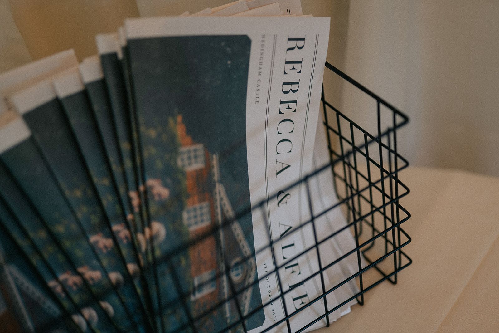 A stack of newspapers in a wire basket with rebecca on the front
