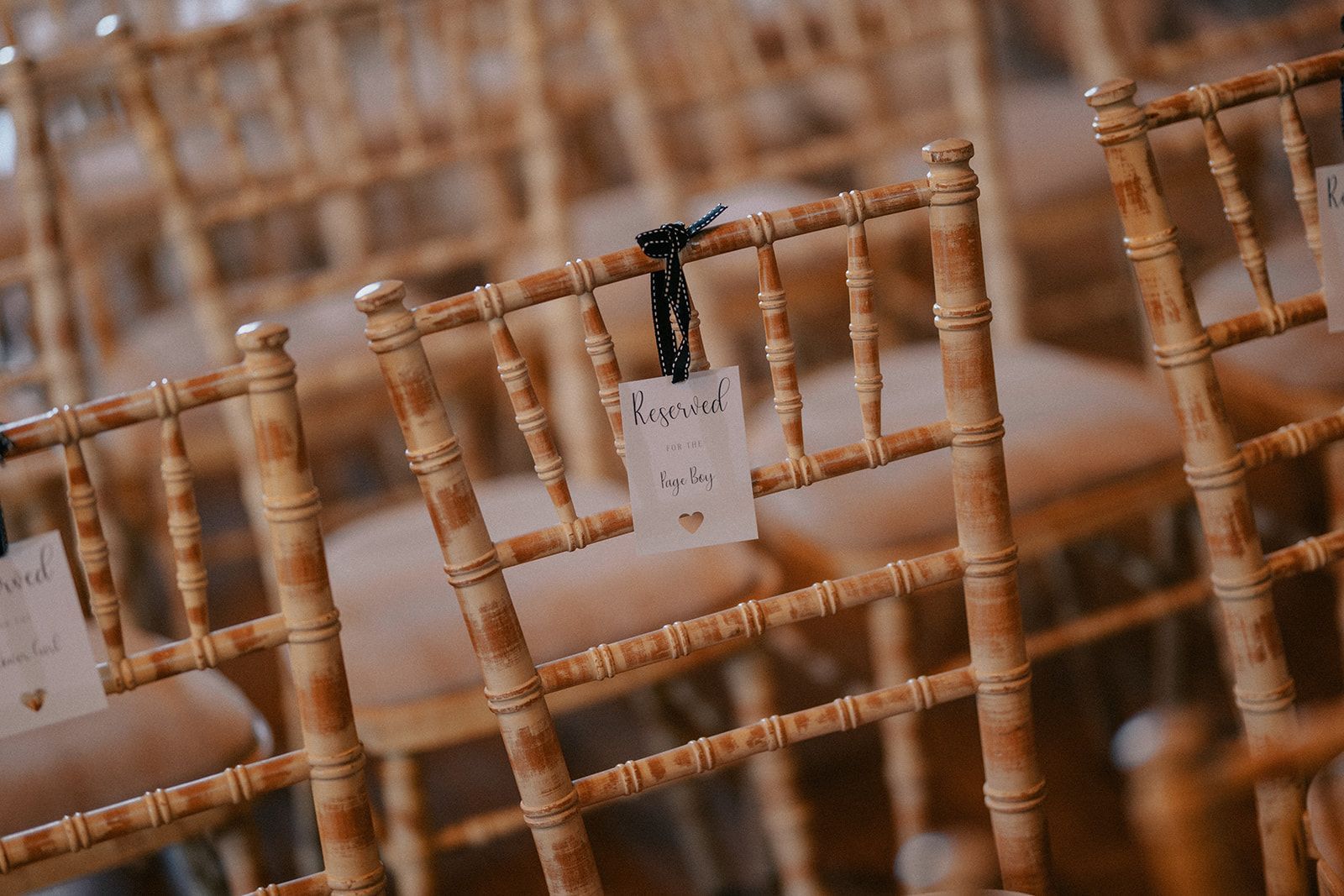 A row of wooden chairs with name tags attached to them.