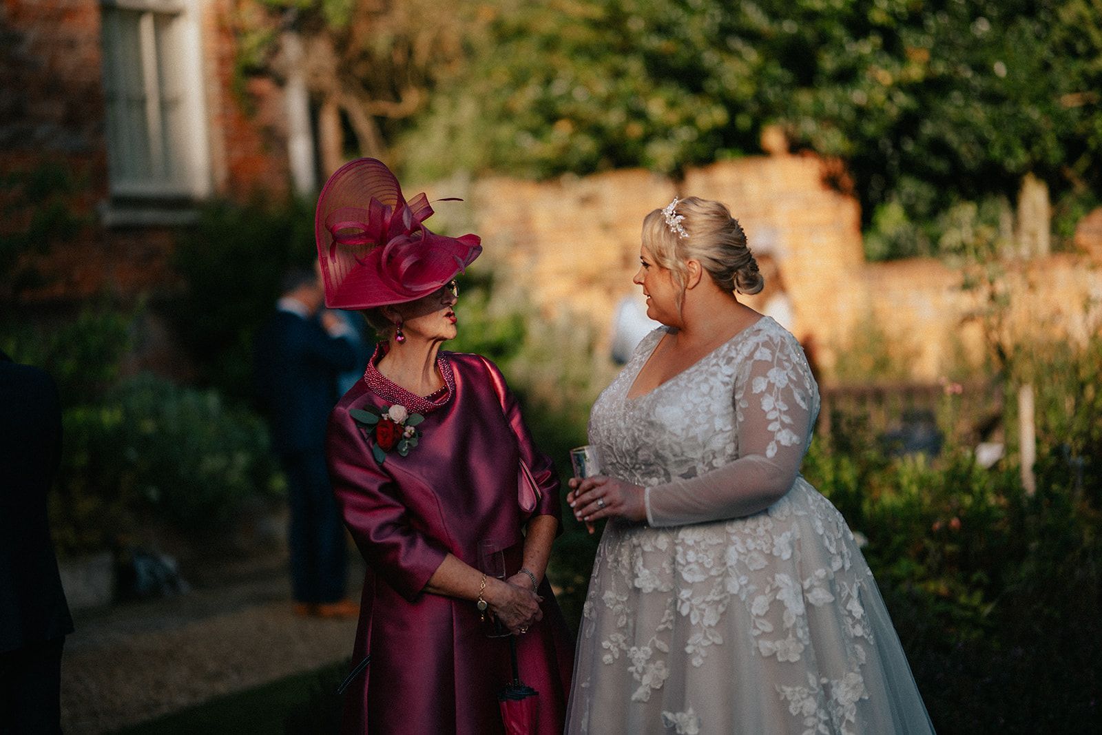 A bride and her mother are standing next to each other in a garden.