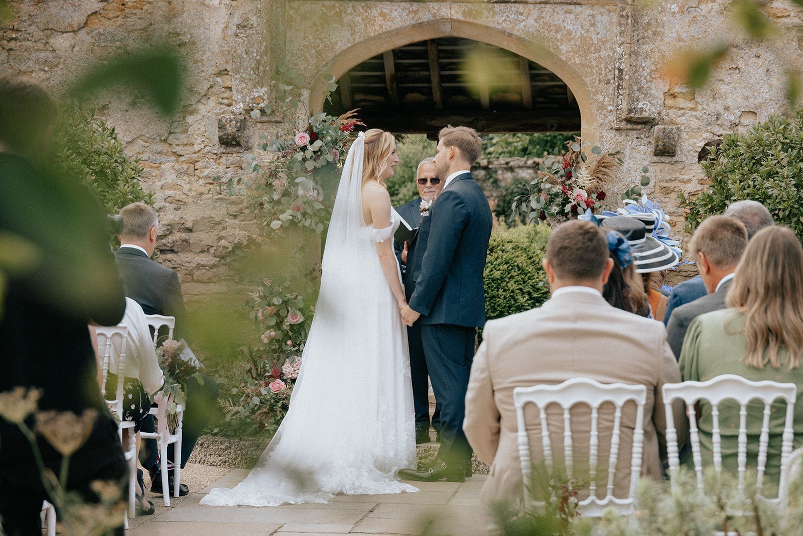 A bride and groom are holding hands during their wedding ceremony.