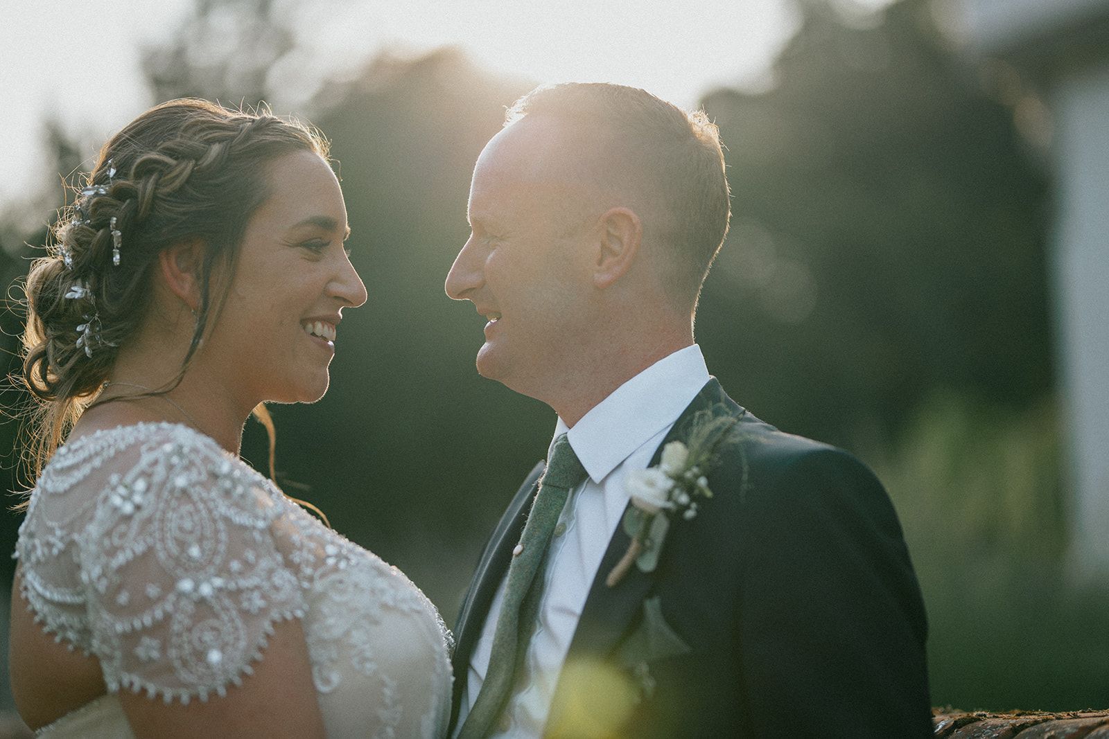 A bride and groom are looking at each other and smiling.