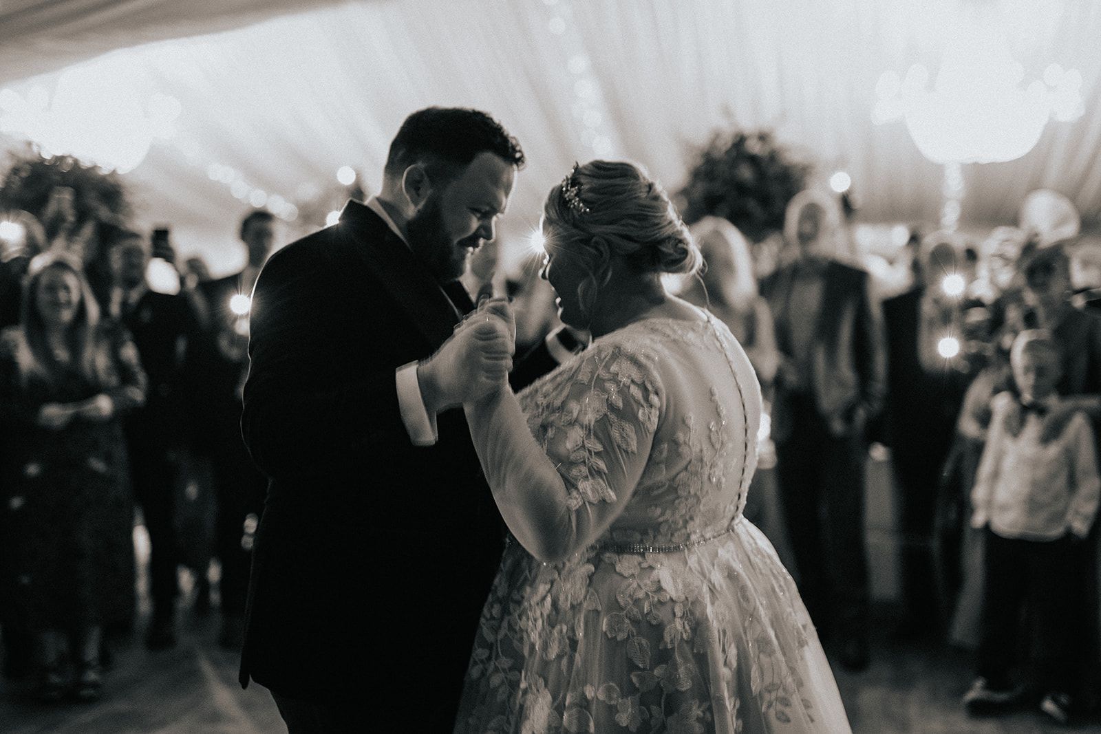 A black and white photo of a bride and groom dancing at their wedding reception.
