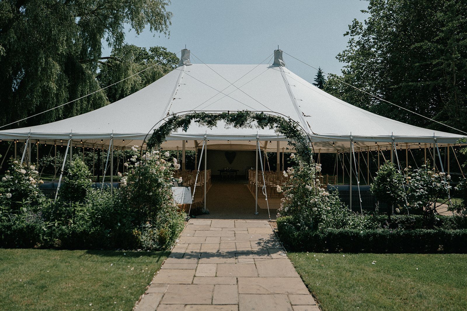 A large white tent is sitting in the middle of a lush green field.