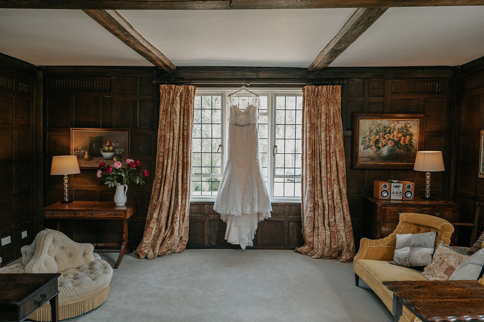 A wedding dress is hanging on a window in a living room.