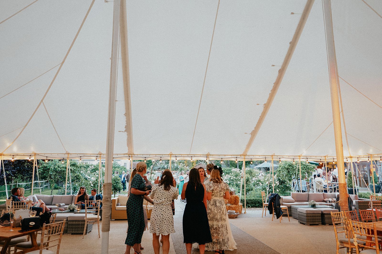 A group of women are dancing under a tent at a wedding reception.