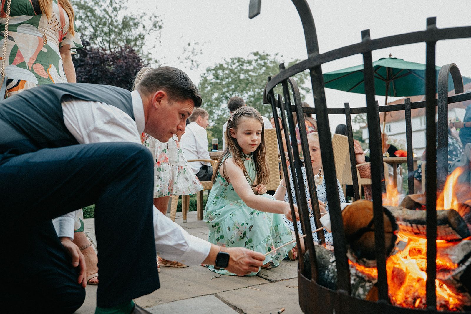 A man and a little girl are sitting around a fire pit.