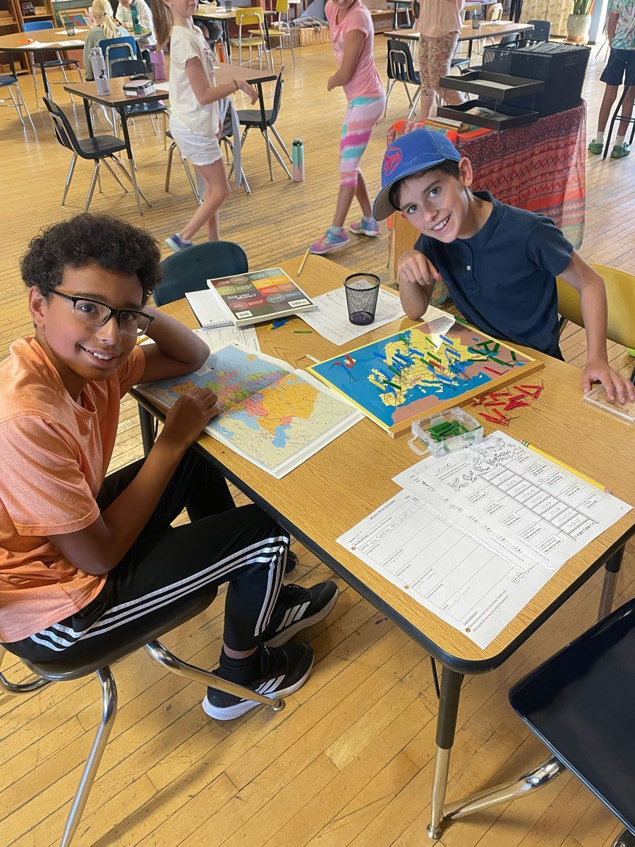Two people smiling at a table with maps and papers.