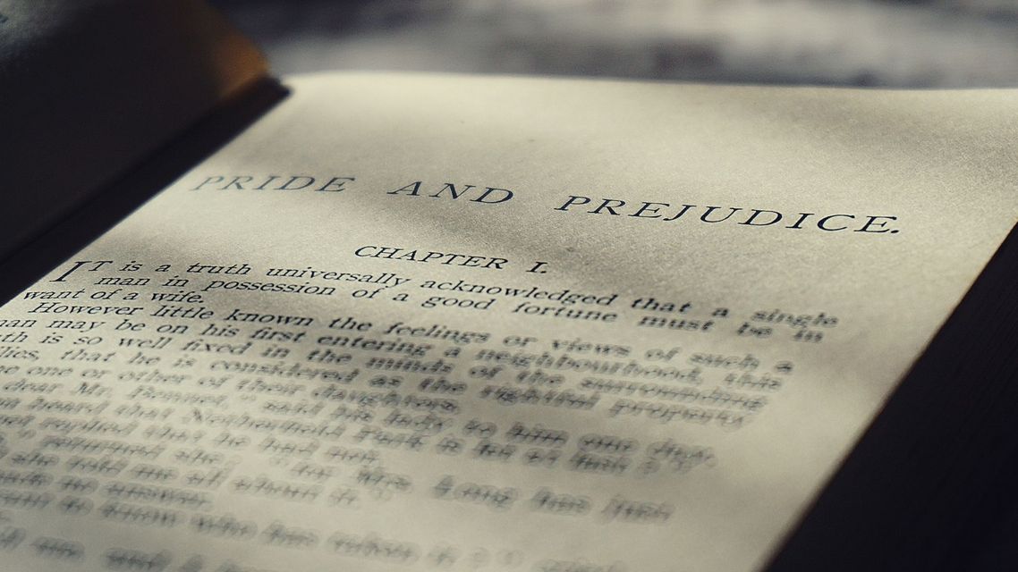 Close-up of a lit printed page with blurred text, lying at an angle on a dark surface.
