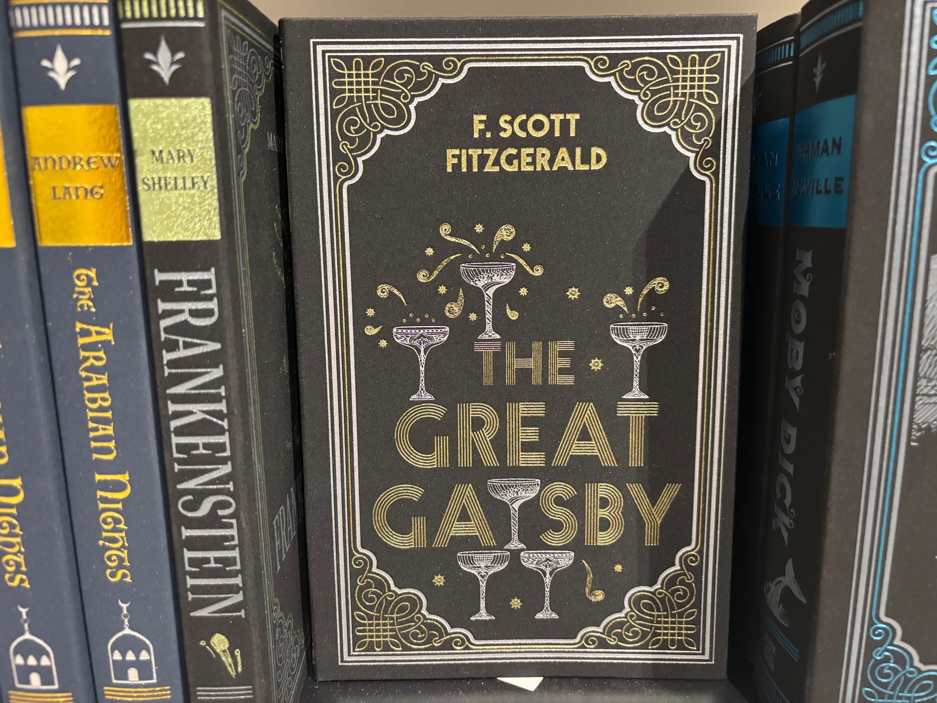 Bookshelf with a centered black-and-gold copy of The Great Gatsby by F. Scott Fitzgerald