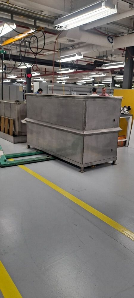 Metal tanks in a factory setting, with yellow floor markings and overhead lighting.