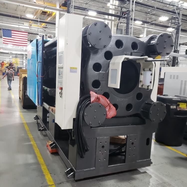 Large industrial machine with blue and gray components, in a factory setting with a US flag.