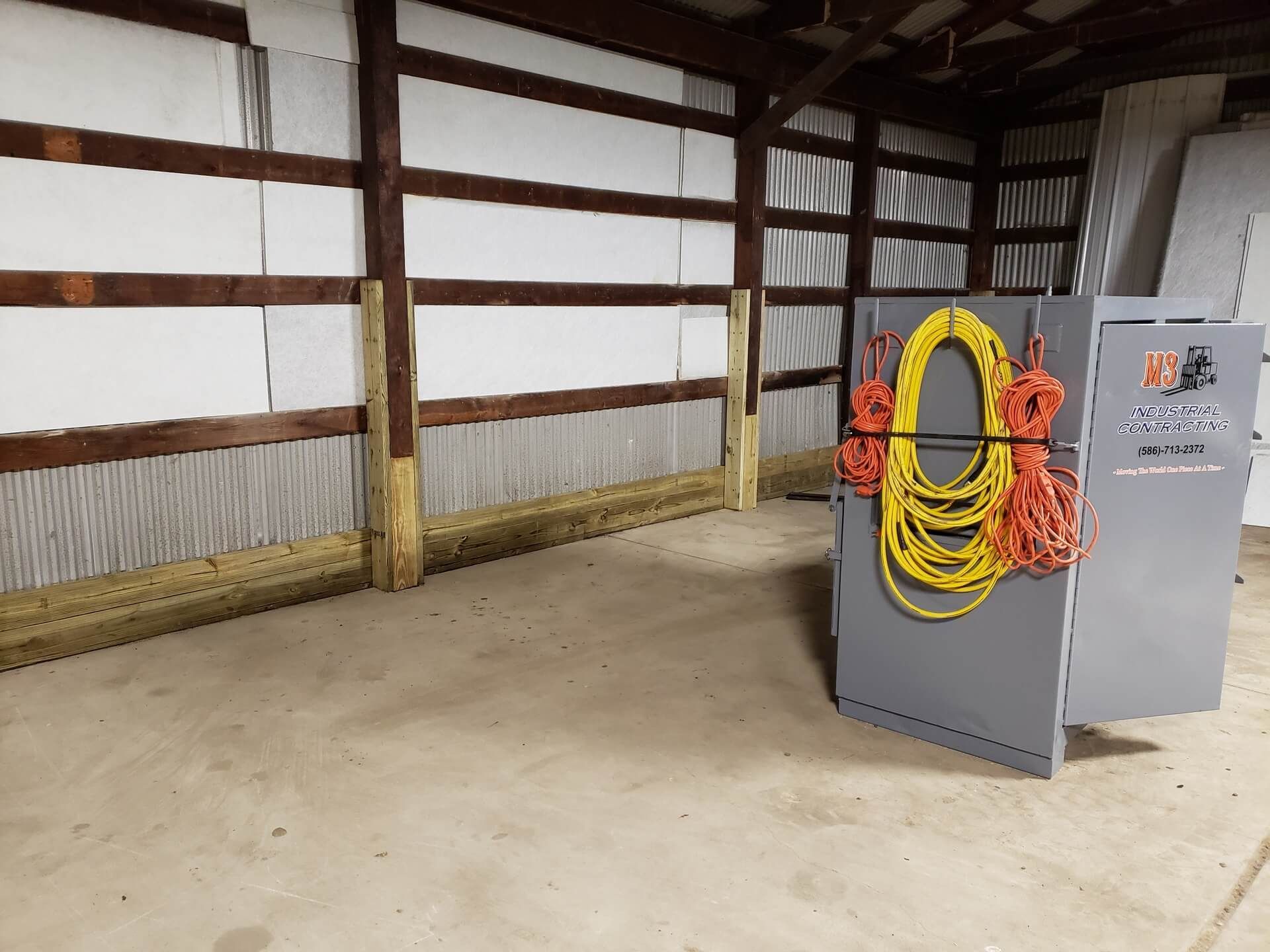 Interior of a barn with a grey cabinet holding coiled cords. The walls are white and brown.