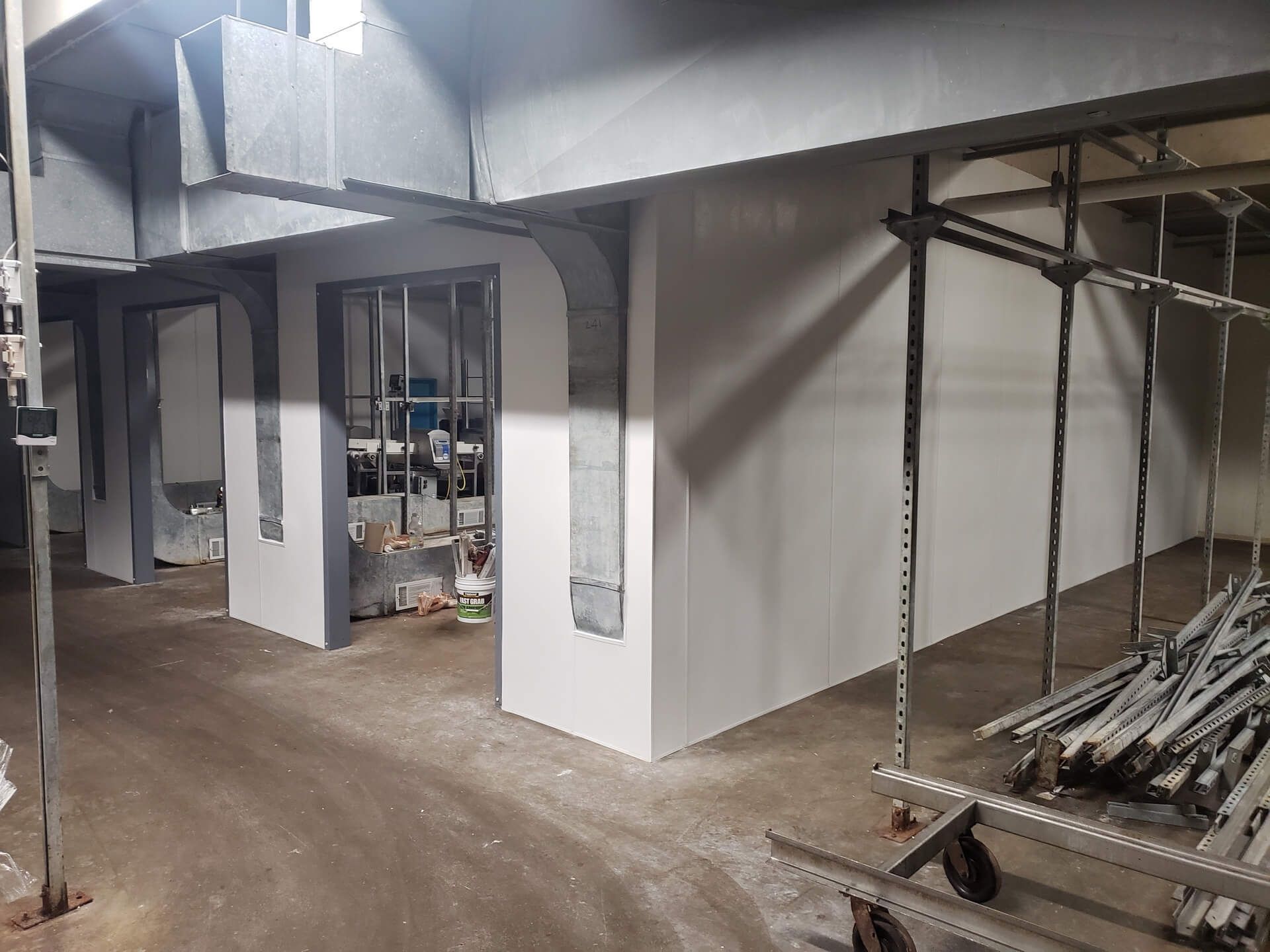 Construction site: white walls being built, with a metal frame window, pipes, and scaffolding.