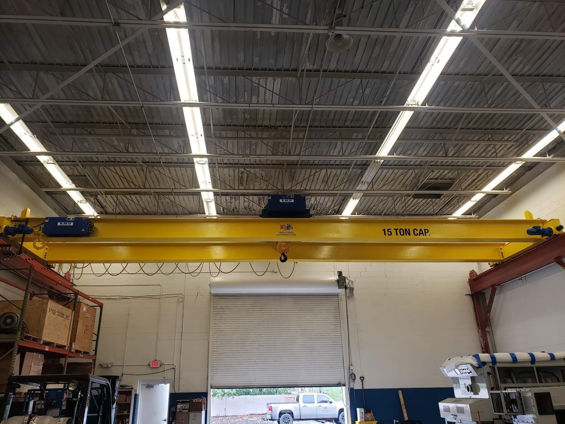 Yellow overhead crane in a warehouse setting, labeled with 