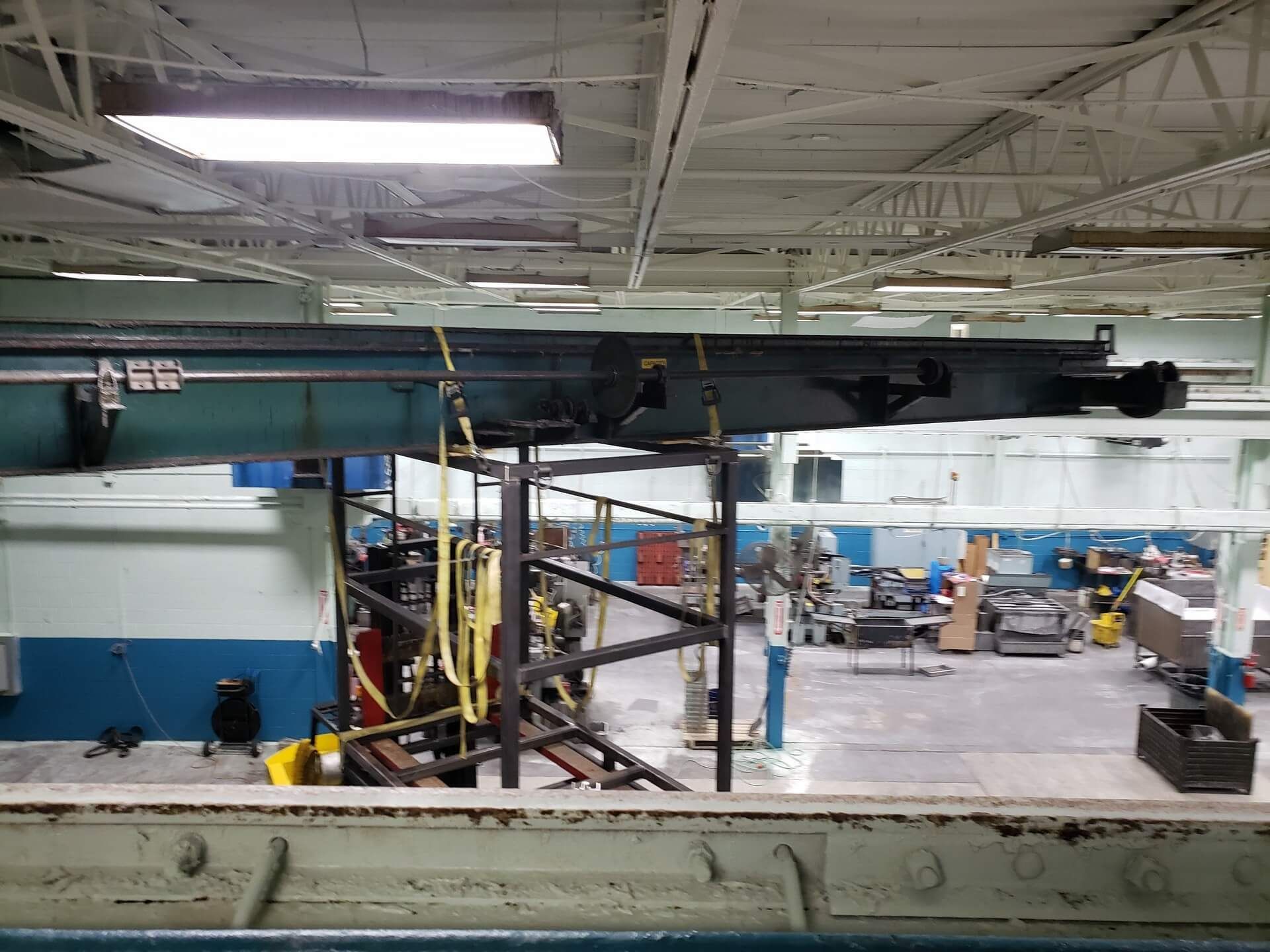 Overhead crane in a factory setting, suspended above machinery.